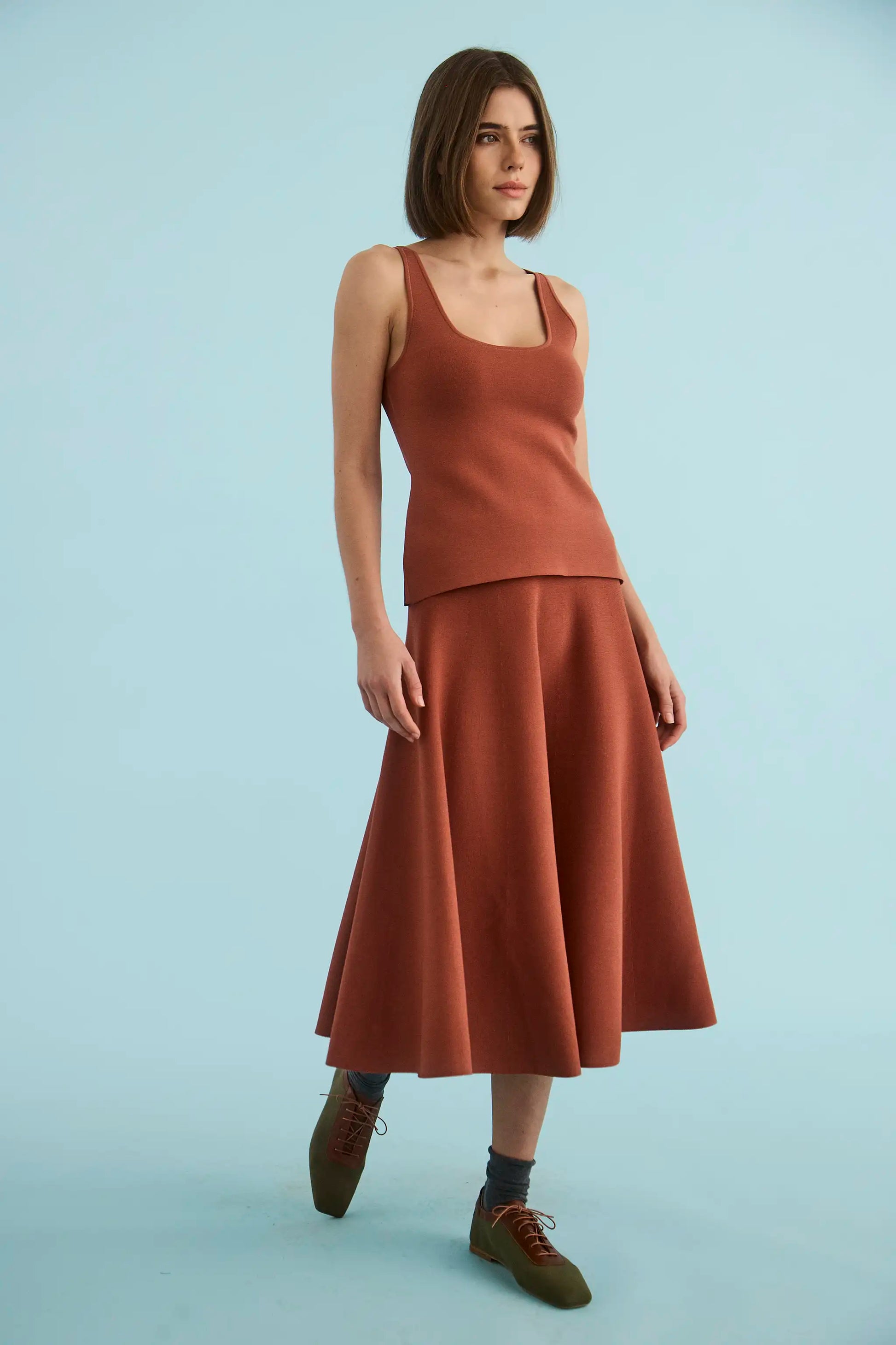 Model wearing rust-colored sleeveless tank cami top with scoop neckline and flared midi skirt