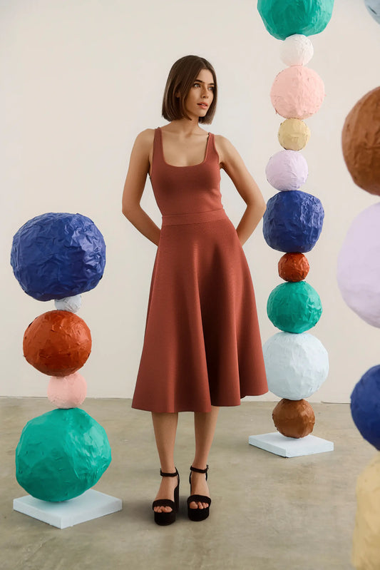 Model wearing Hunter Bell Joan midi skirt in rust with matching tank top and black platform heels