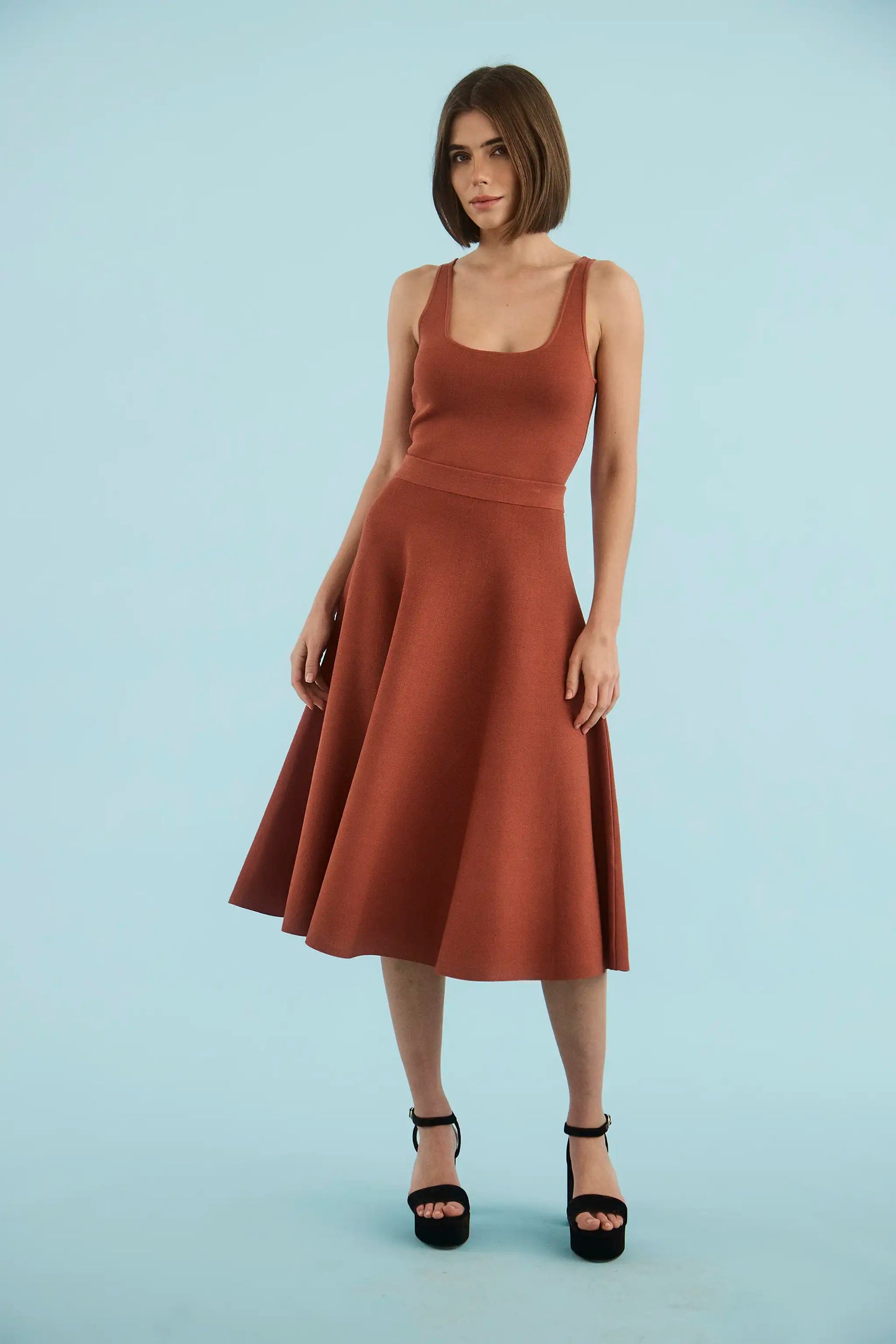 Model wearing Hunter Bell Joan midi skirt in rust terracotta with black platform heels