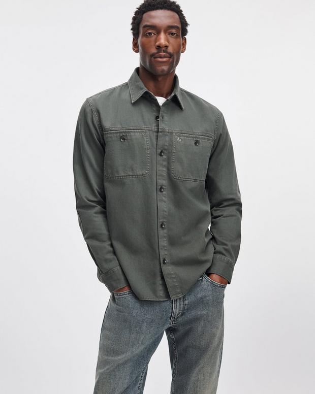 Male model wearing dark green Rag & Bone denim workwear shirt with dual chest pockets and jeans