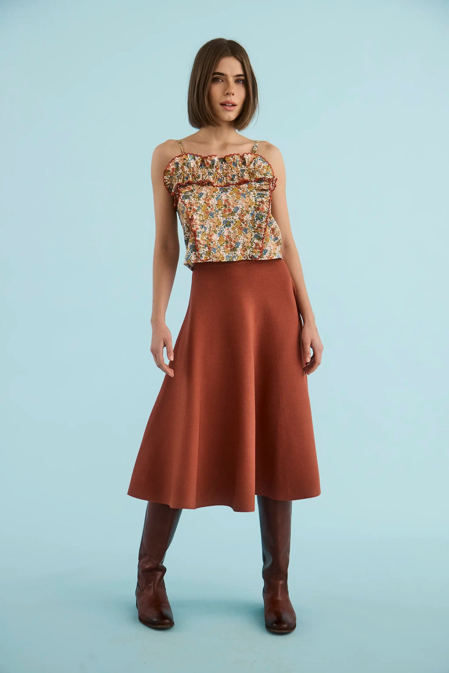 Model wearing Hunter Bell Joan Skirt in rust, a midi A-line knit skirt with brown boots