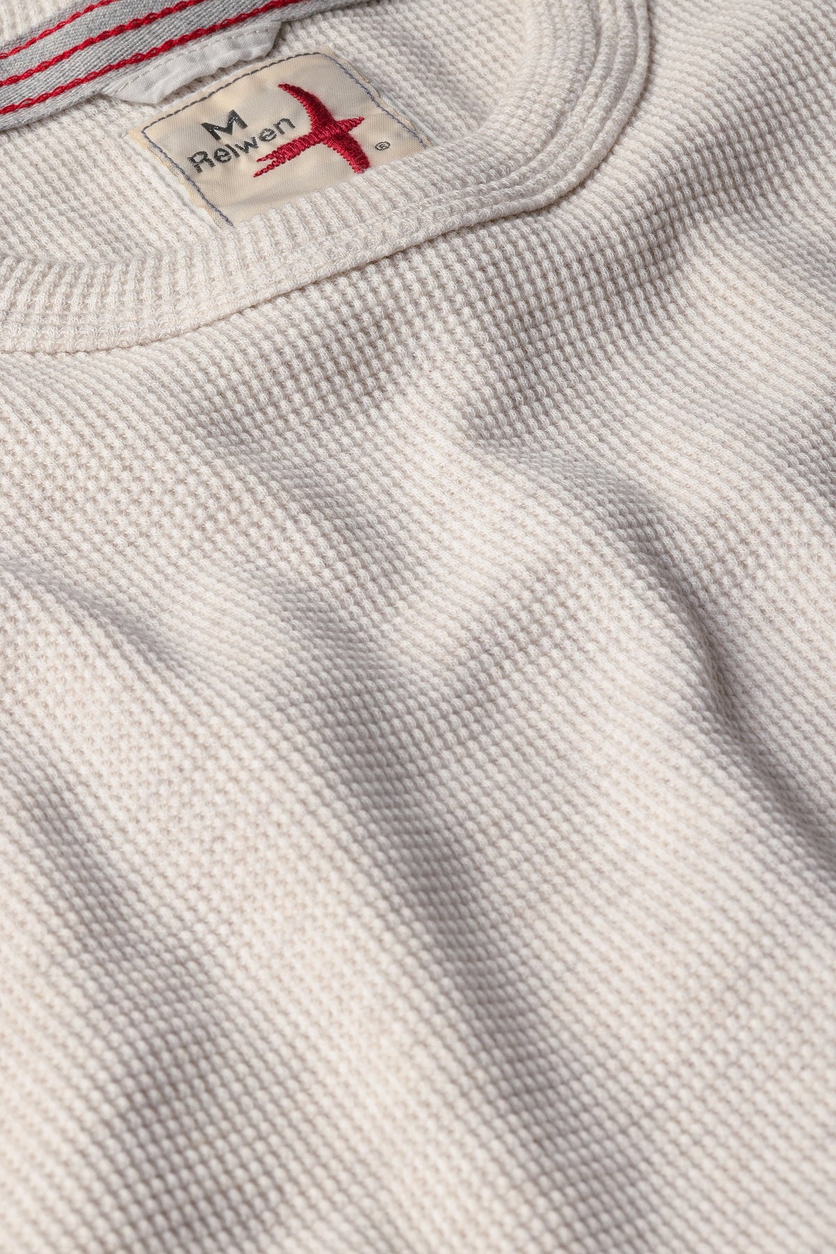 Close-up of Relwen Bi-Waffle Crewneck in oatmeal heather with textured waffle knit fabric and brand label