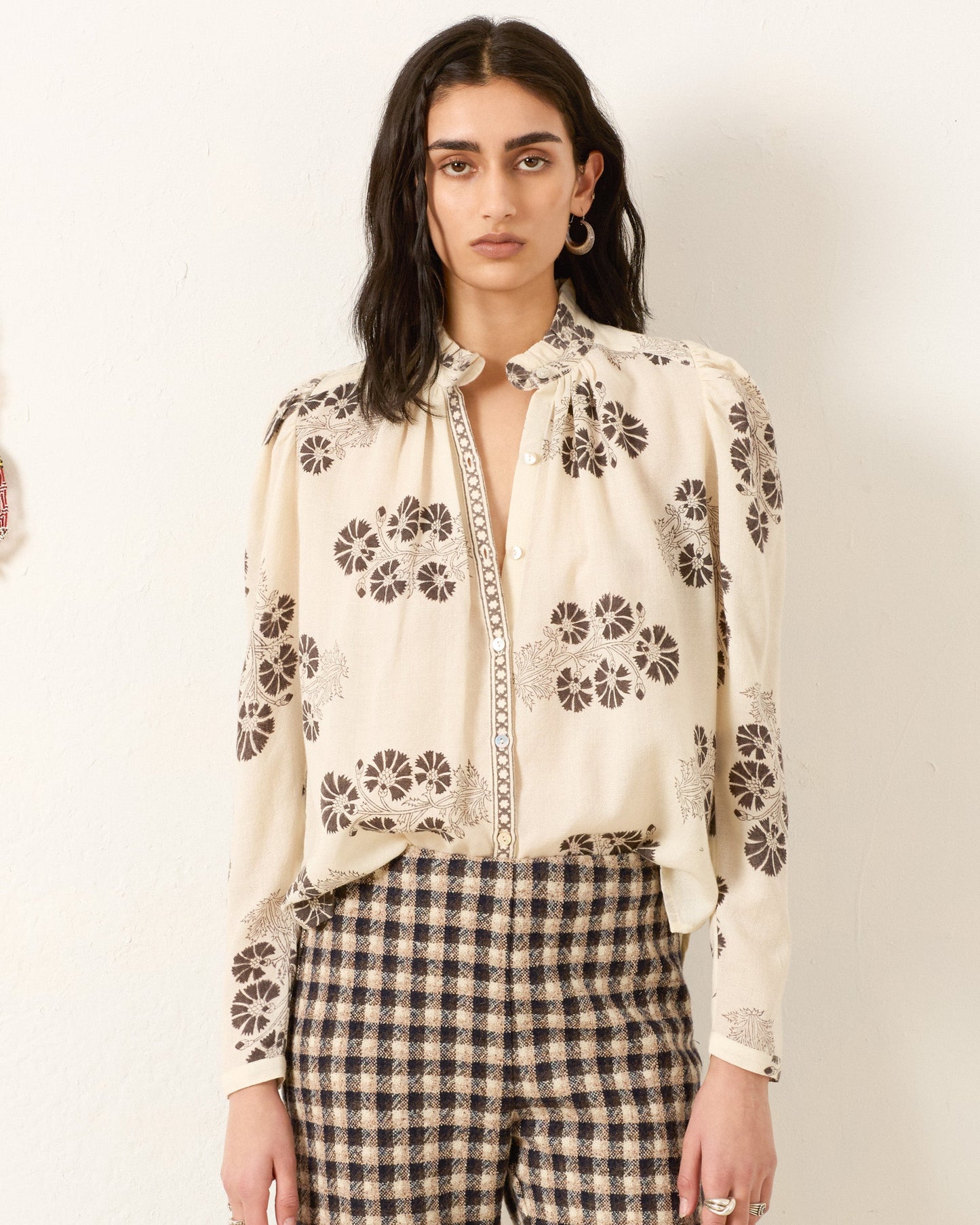 Model wearing cream colored button-up shirt with brown floral print and checkered pants