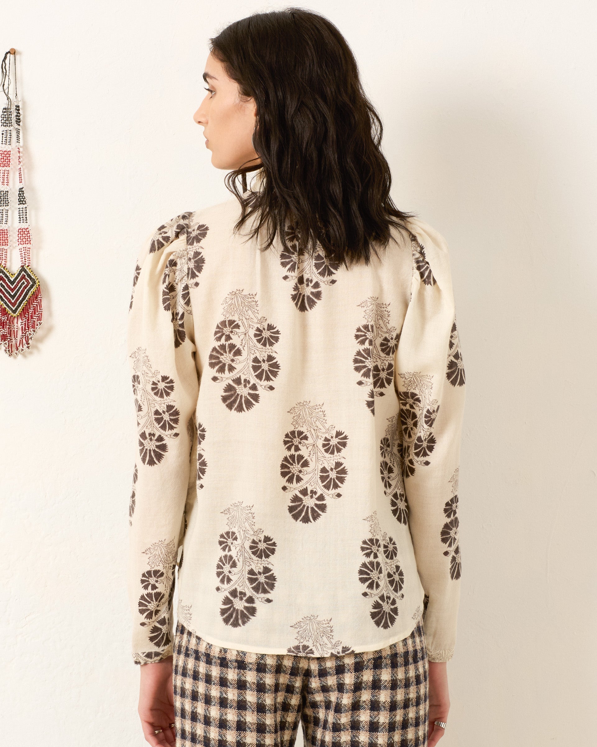 Woman wearing white cream silk shirt with brown java flower print pattern from behind