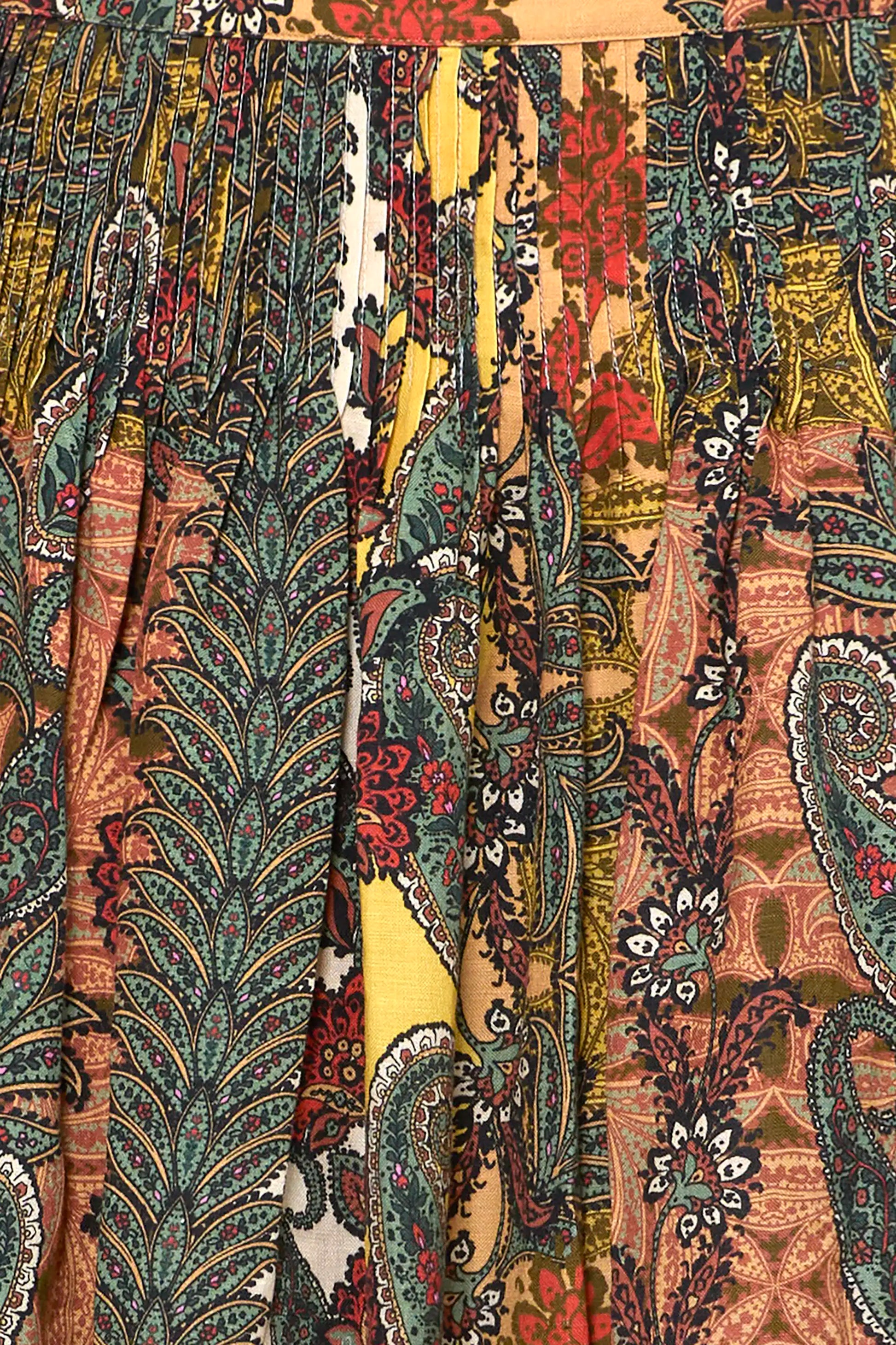 Close-up of pleated skirt featuring mixed paisley and botanical tapestry prints in earthy tones