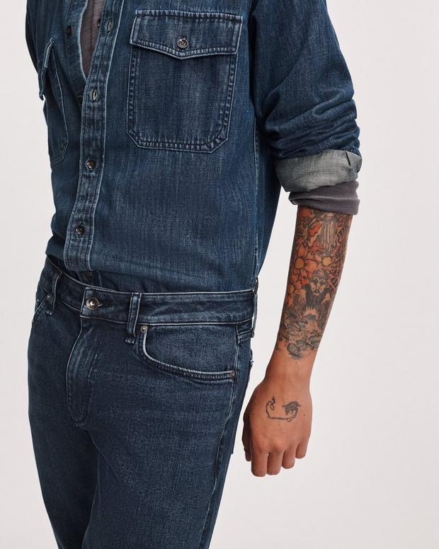 Model wearing dark indigo Rag and Bone Fit 3 Athletic stretch jeans with denim shirt