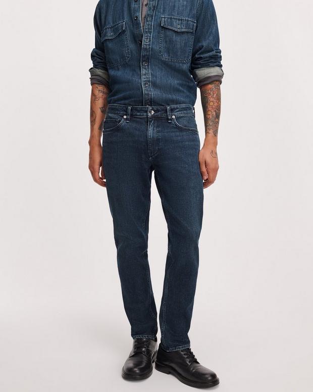 Male model wearing dark indigo Rag & Bone Fit 3 Athletic stretch jeans with denim shirt