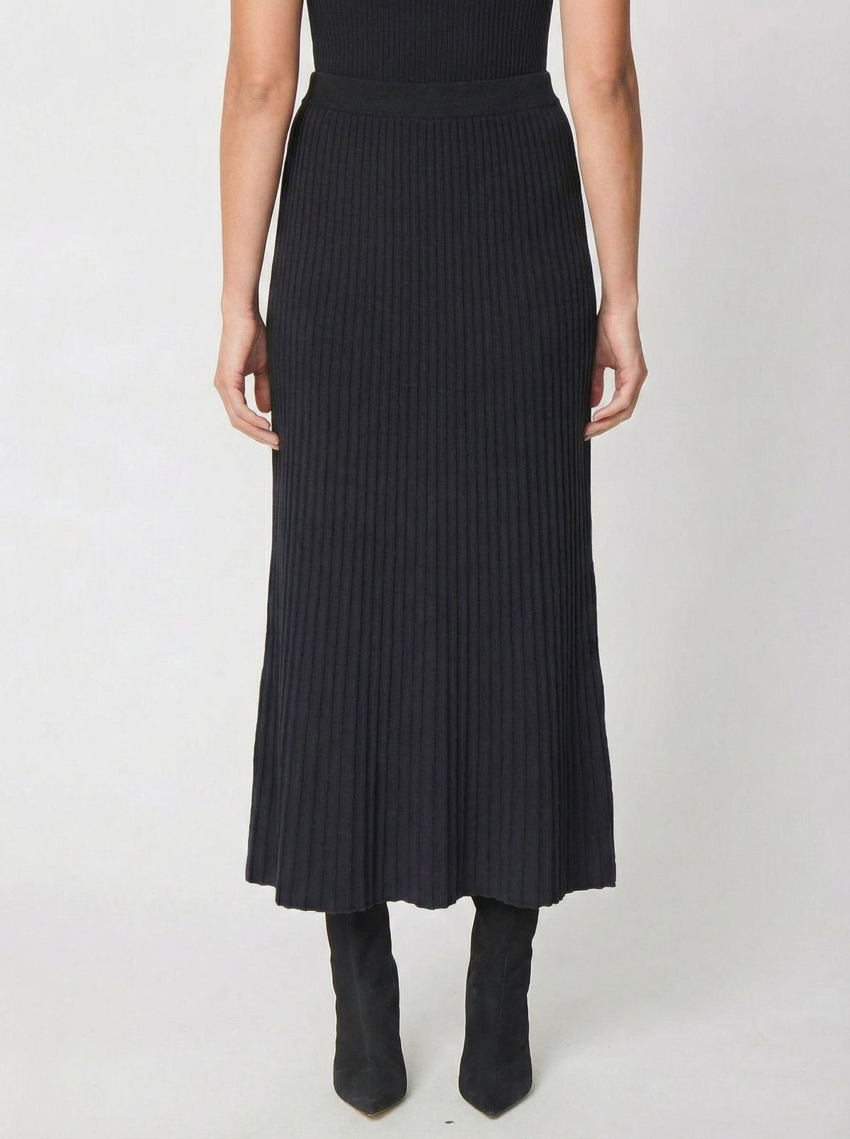 Black ribbed knit midi skirt with flared hem worn with black boots