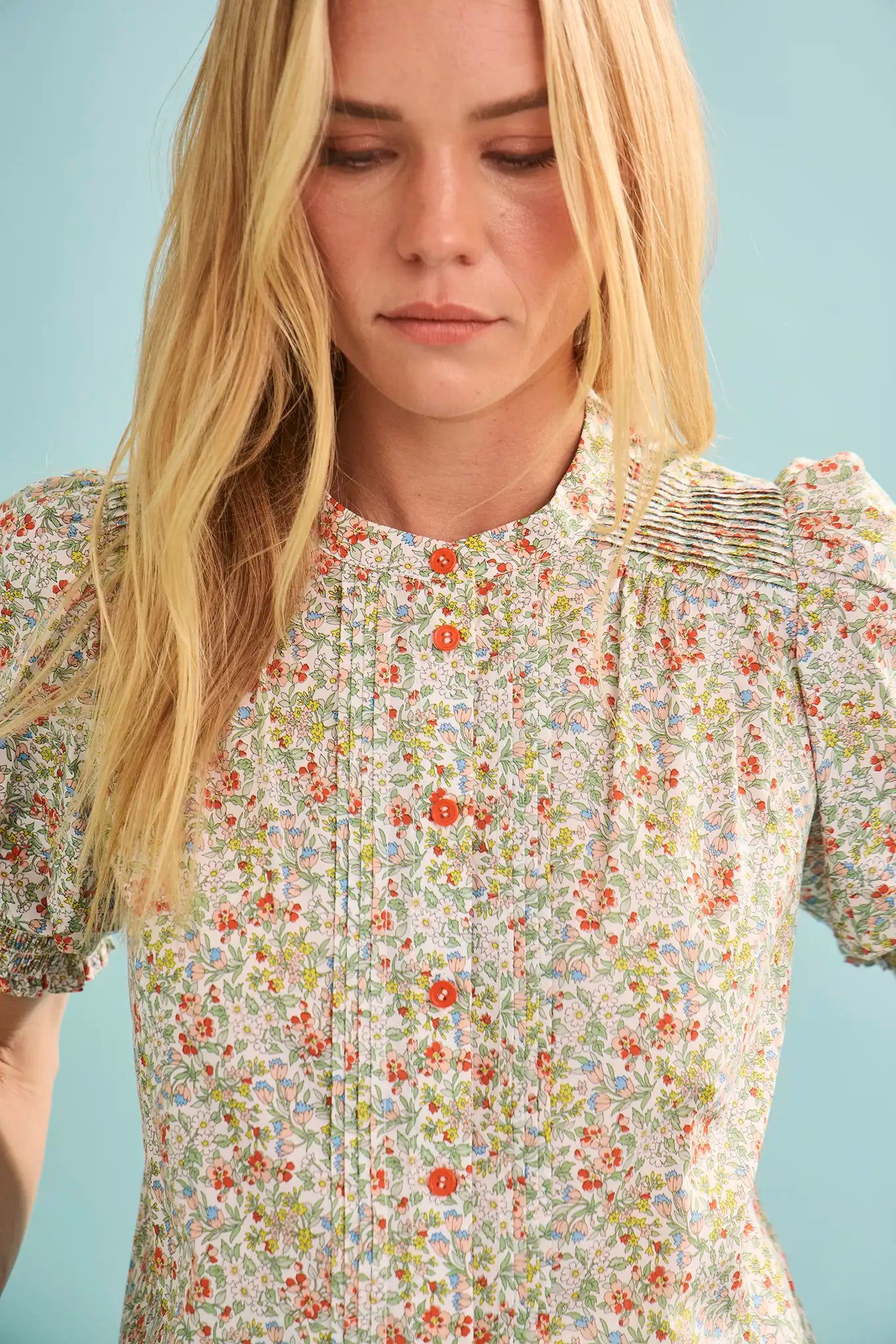 Woman wearing floral print blouse with coral and multicolor botanical pattern