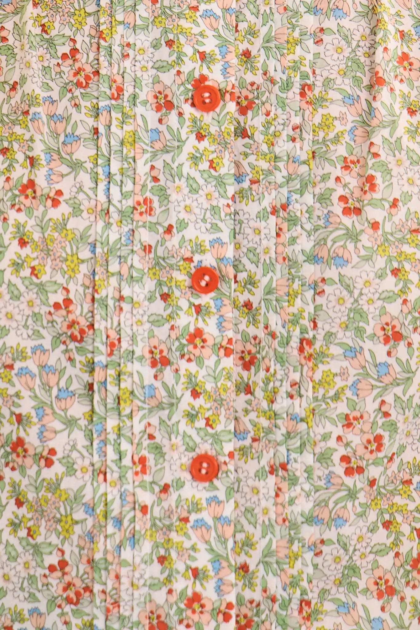 Close-up of floral print top with coral orange buttons and delicate multicolored flower pattern