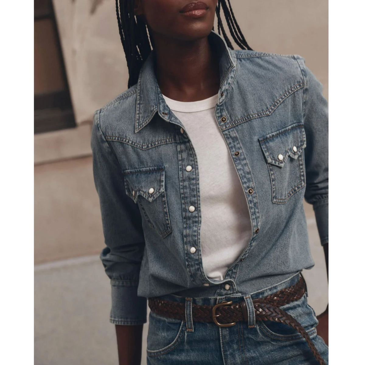Model wearing open medium blue denim western shirt with snap buttons over white tee