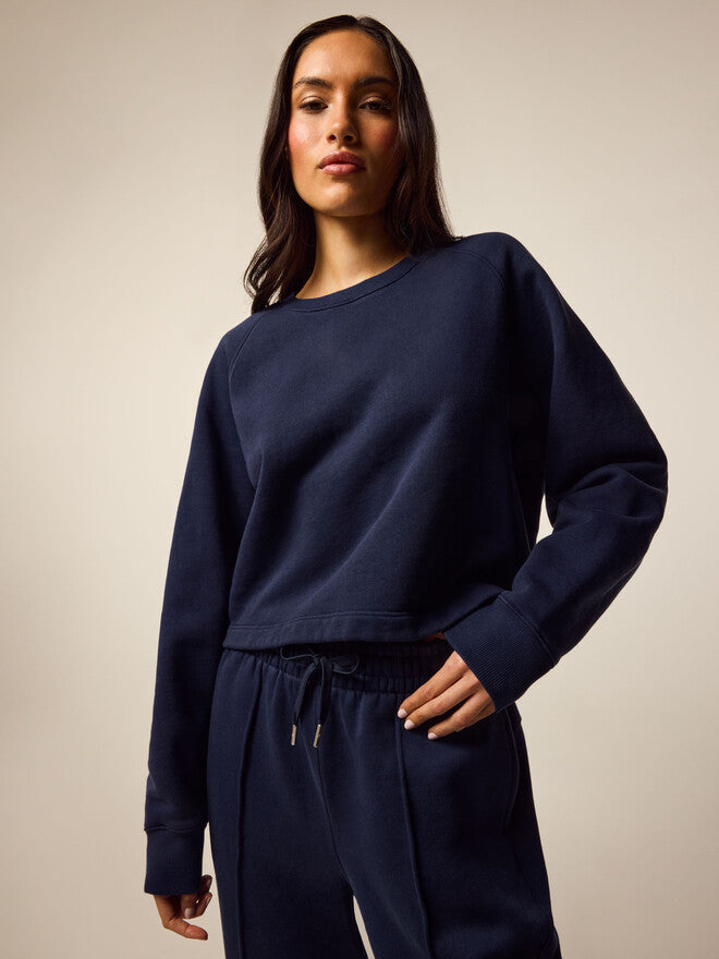 Woman wearing navy cropped crewneck sweatshirt with matching navy jogger pants