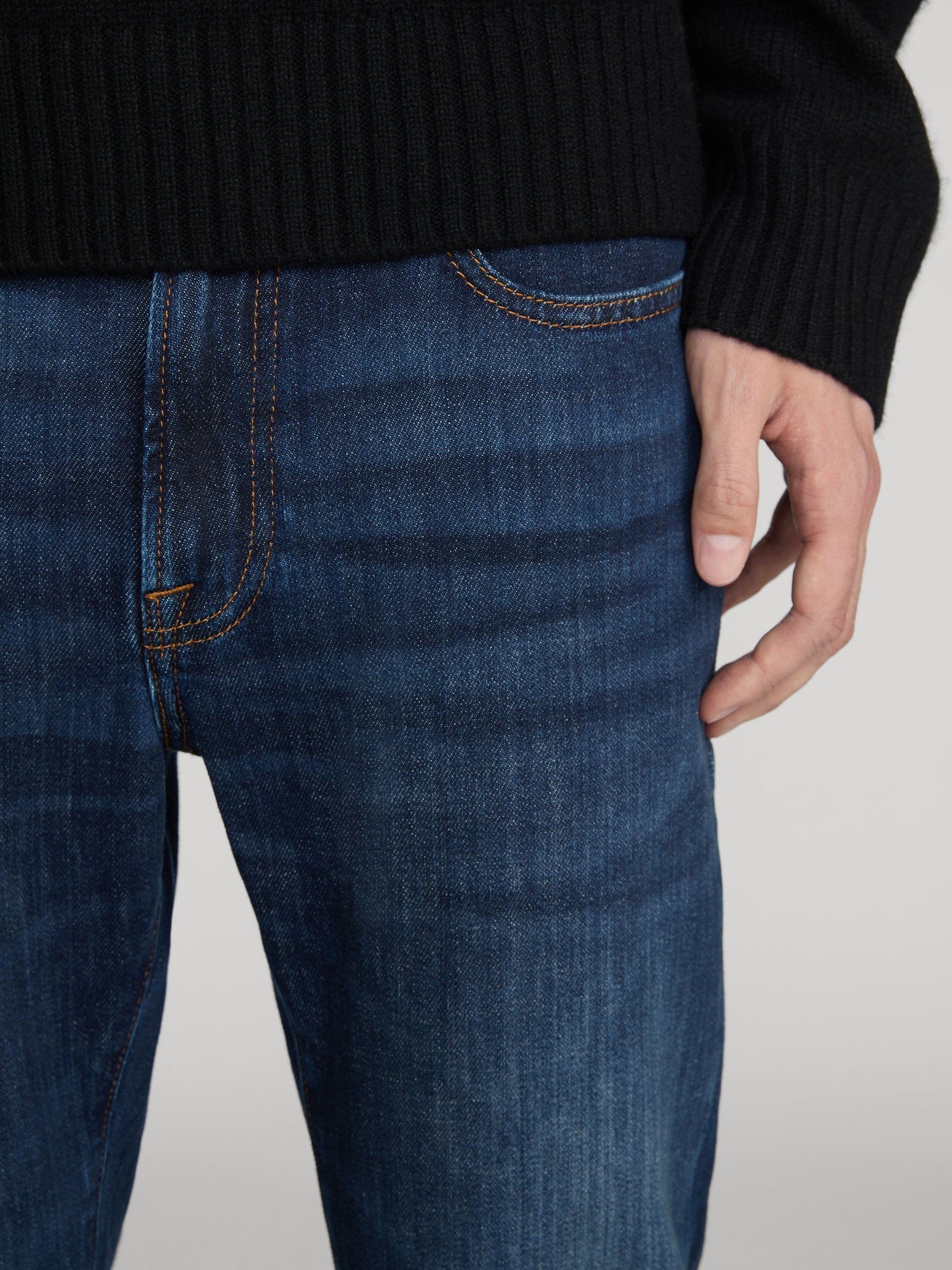 Close-up detail of Frame L'Homme Slim jeans in dark indigo with orange contrast stitching