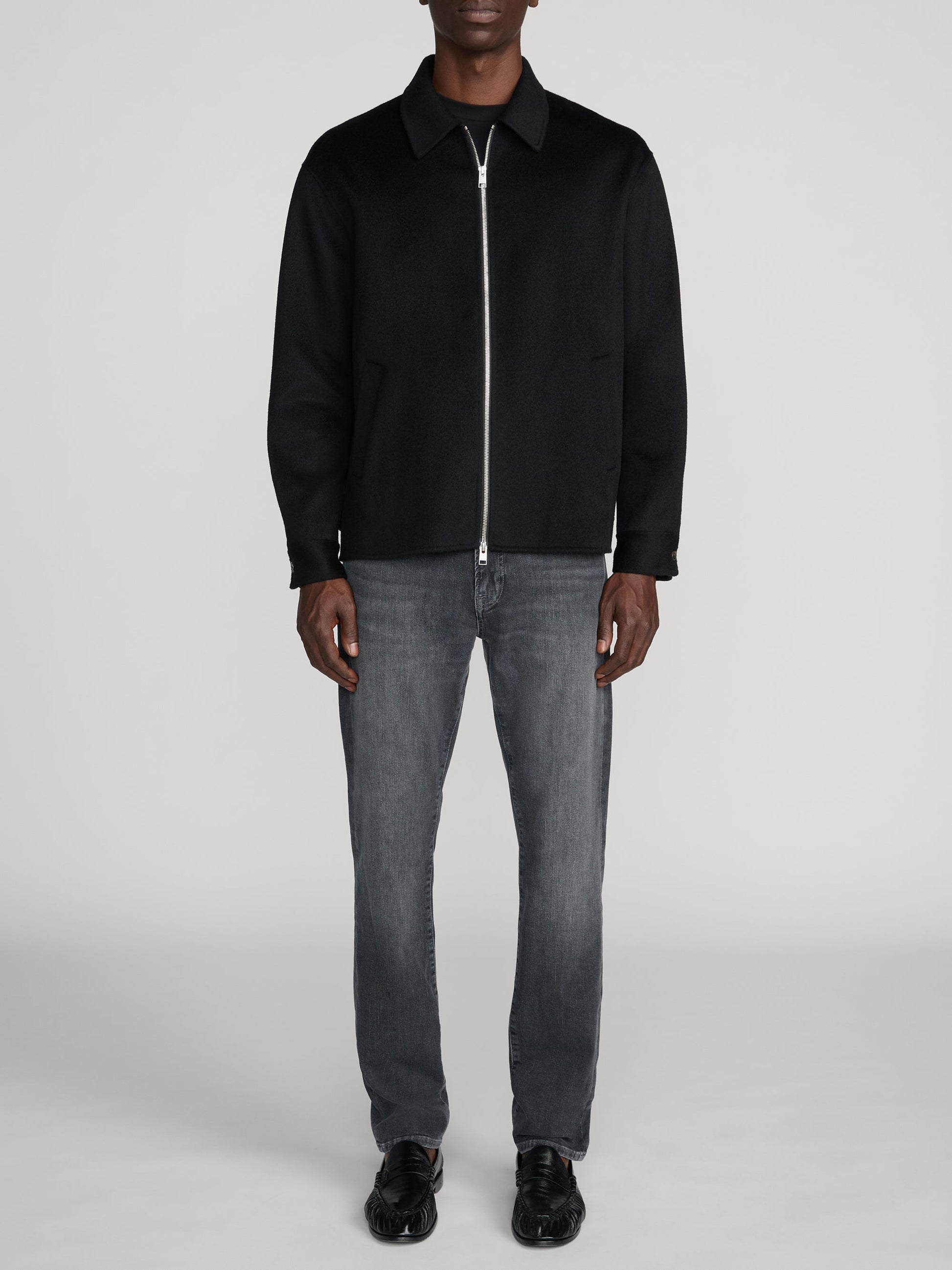 Man wearing Frame L'Homme Slim jeans in Midnight Ash grey wash with black zip jacket