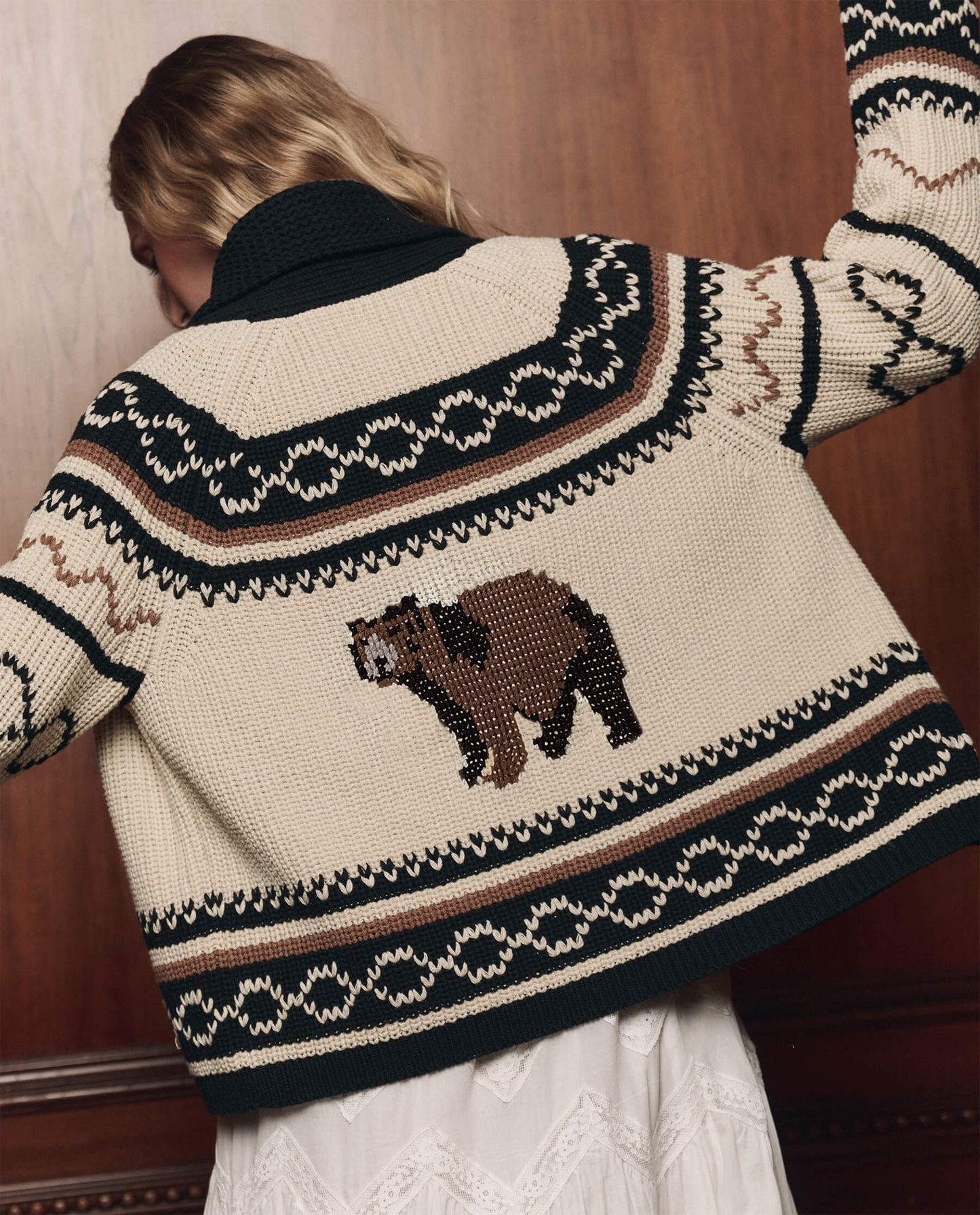 Model wearing cream and black Fair Isle cardigan with brown bear motif on back