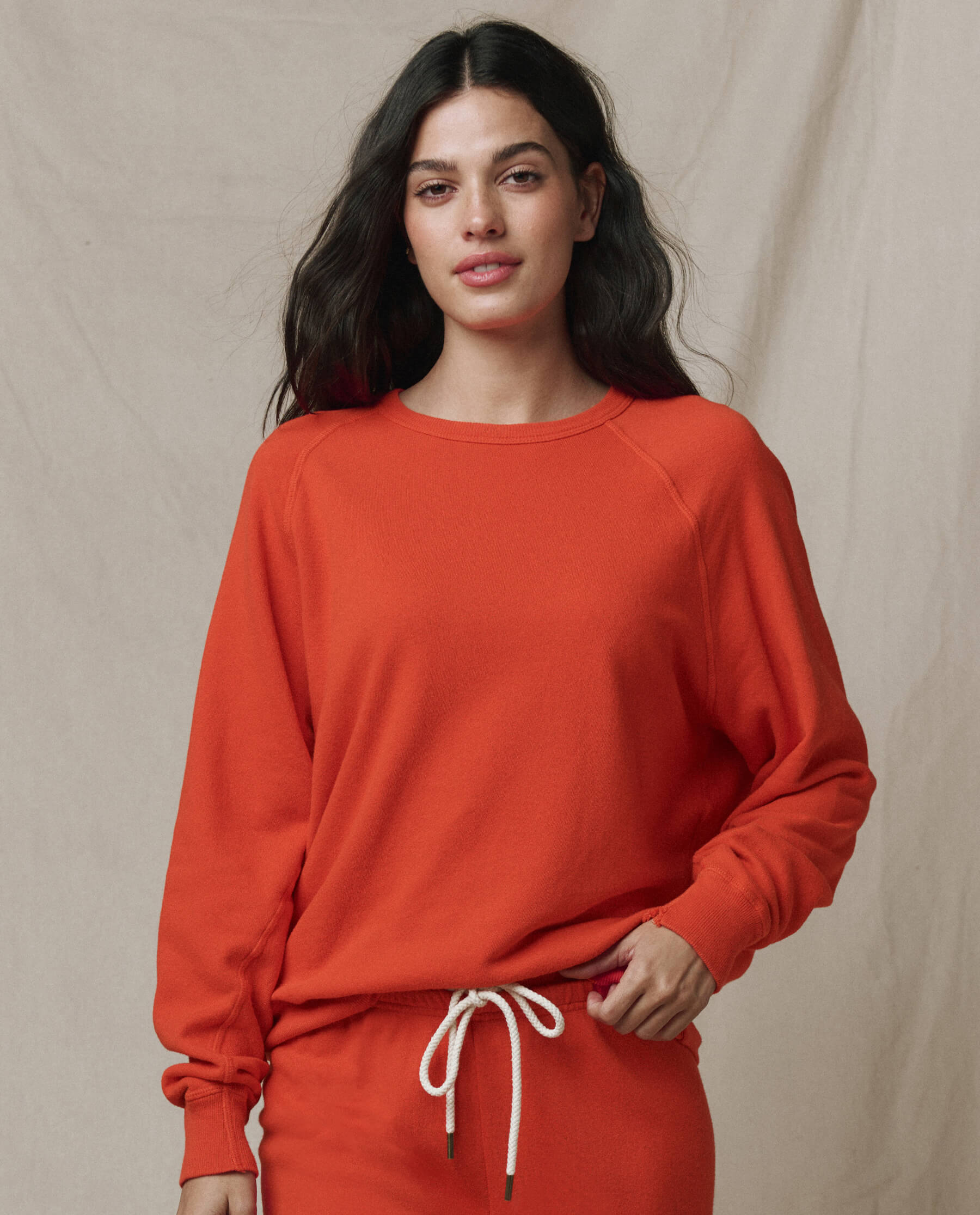 Woman wearing orange-red college sweatshirt with matching drawstring pants