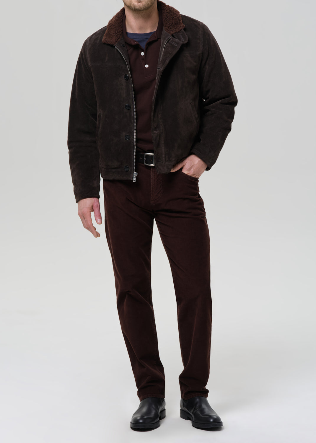 Male model wearing dark brown suede jacket with sherpa collar, matching corduroy pants and black boots