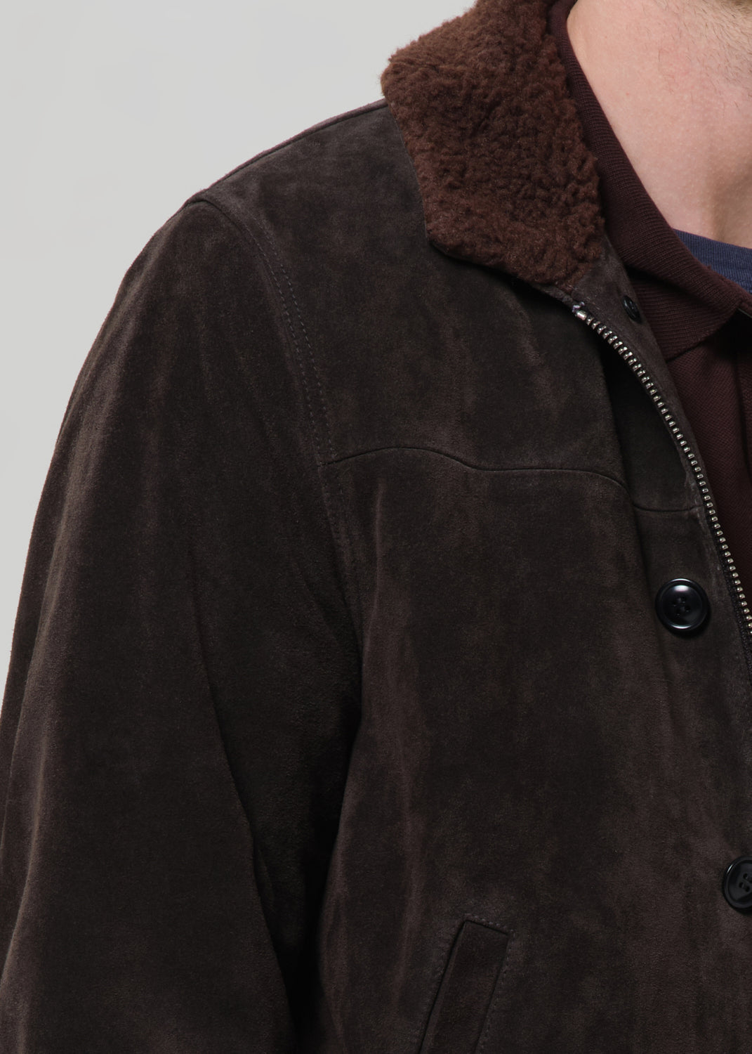 Close-up detail of dark brown suede jacket with sherpa collar and black buttons