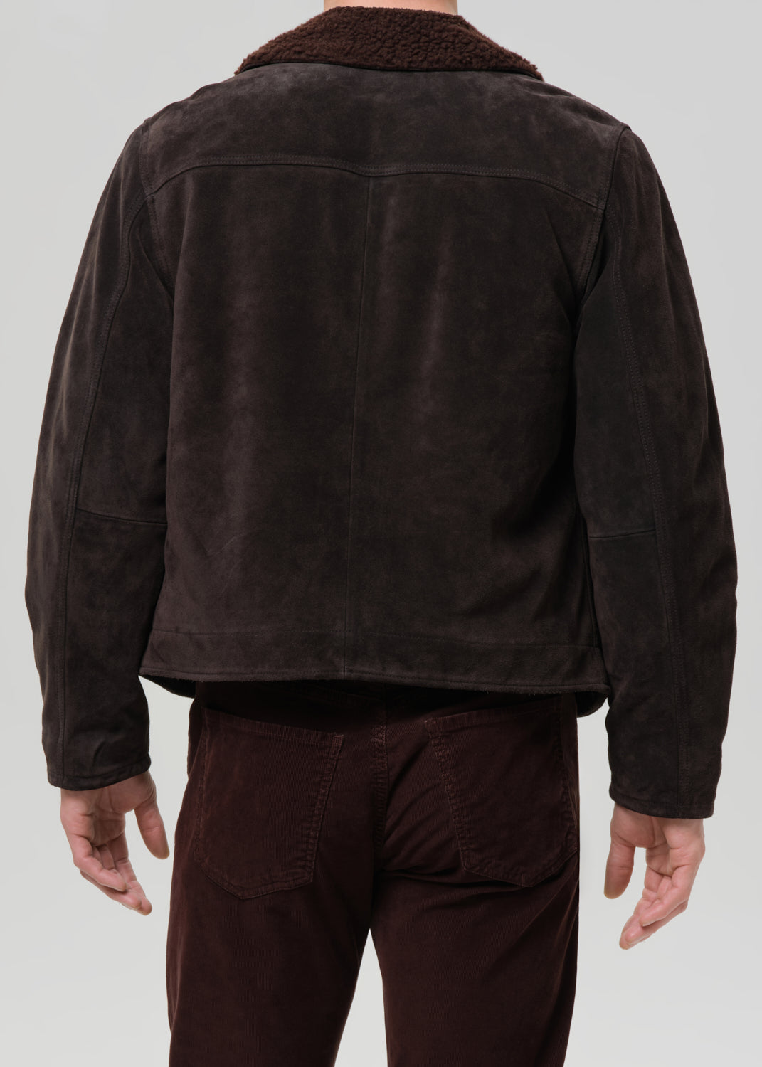 Back view of dark brown suede jacket with sherpa collar and corduroy pants