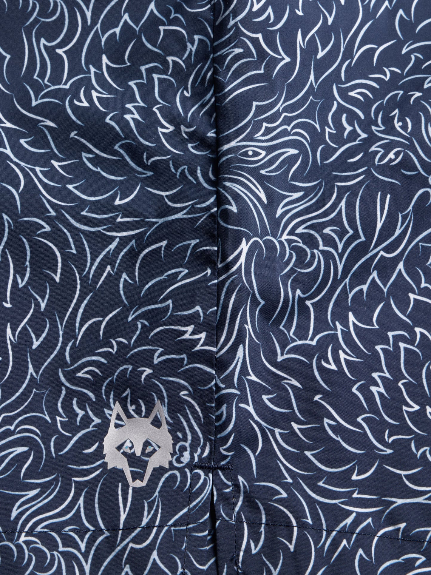 Close-up detail of navy blue swim shorts with white floral pattern and Greyson logo