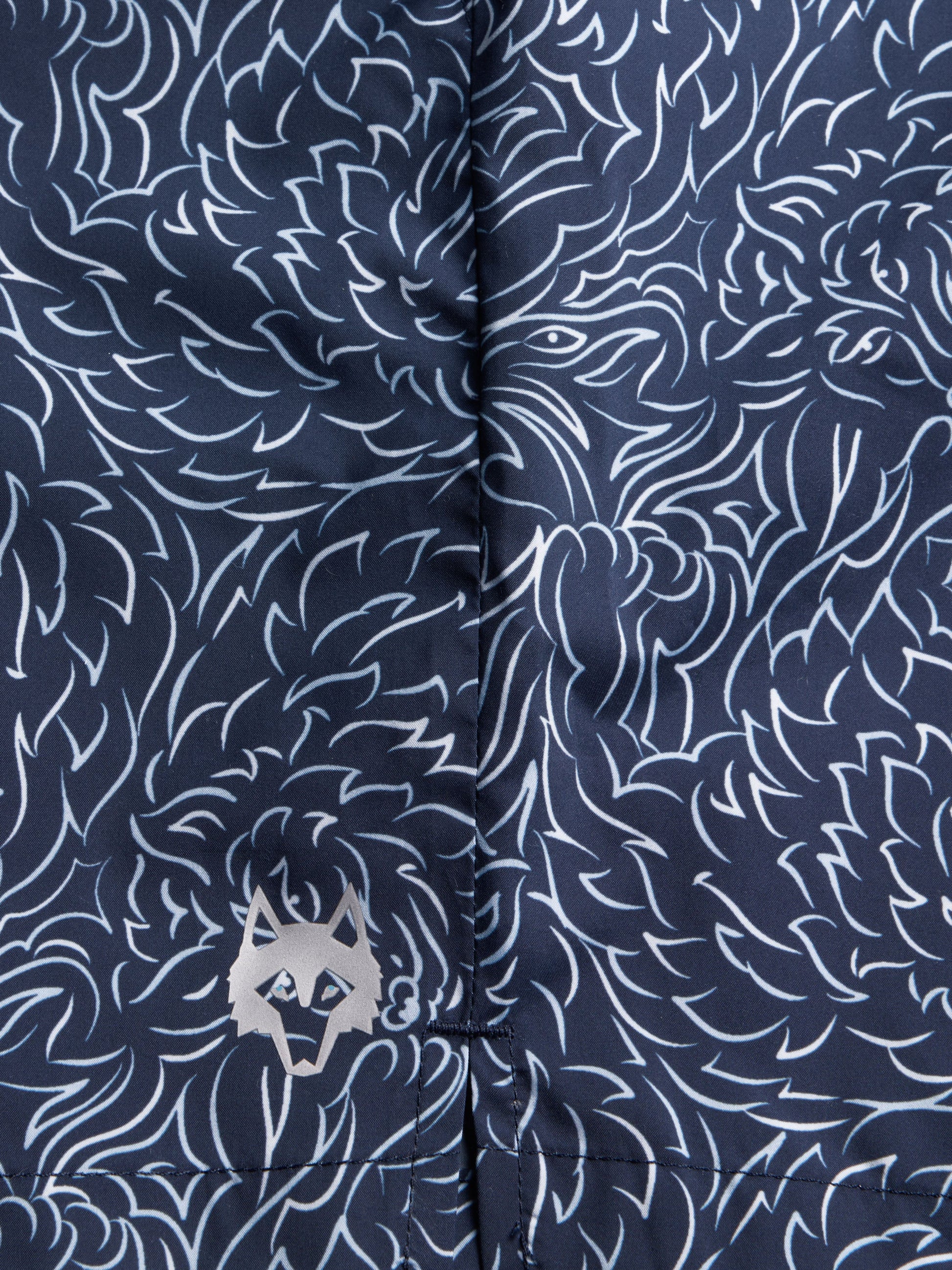Close-up detail of navy blue swim shorts with white floral pattern and Greyson logo