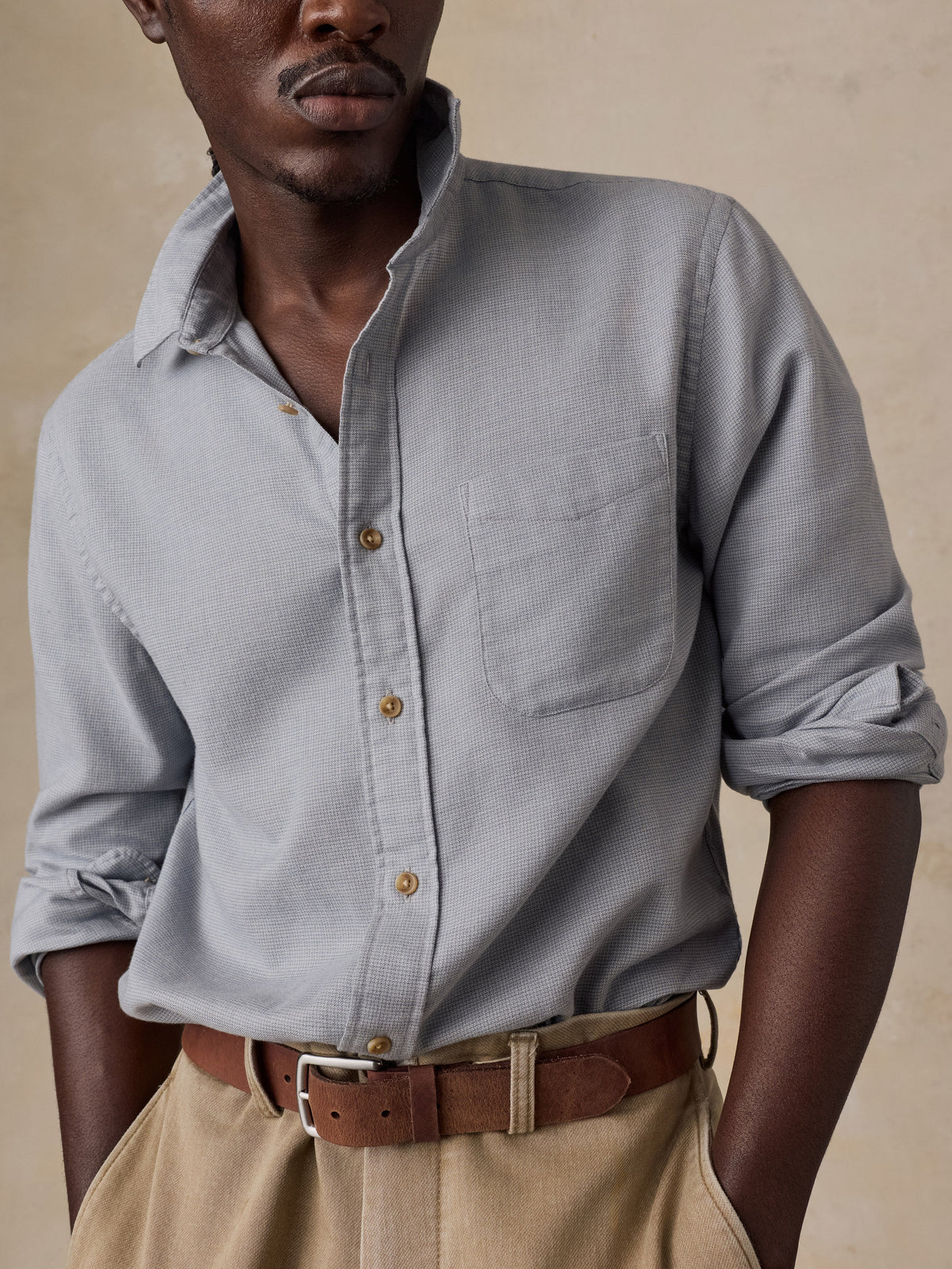 Male model wearing Faherty Timberline Brushed Twill Shirt in mineral grey with rolled sleeves