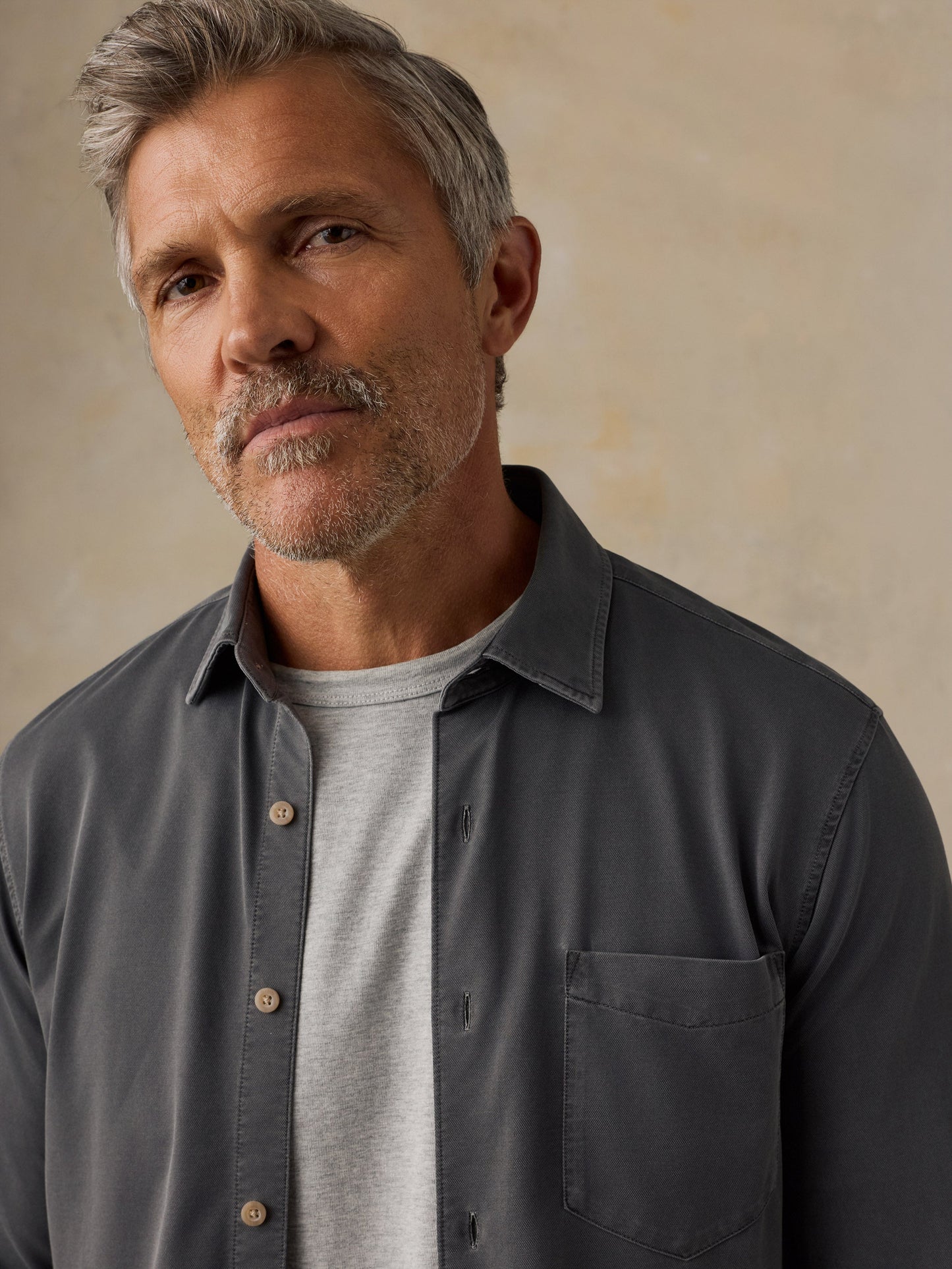 Male model wearing Faherty Costa Piqué Shirt in dark charcoal over gray t-shirt