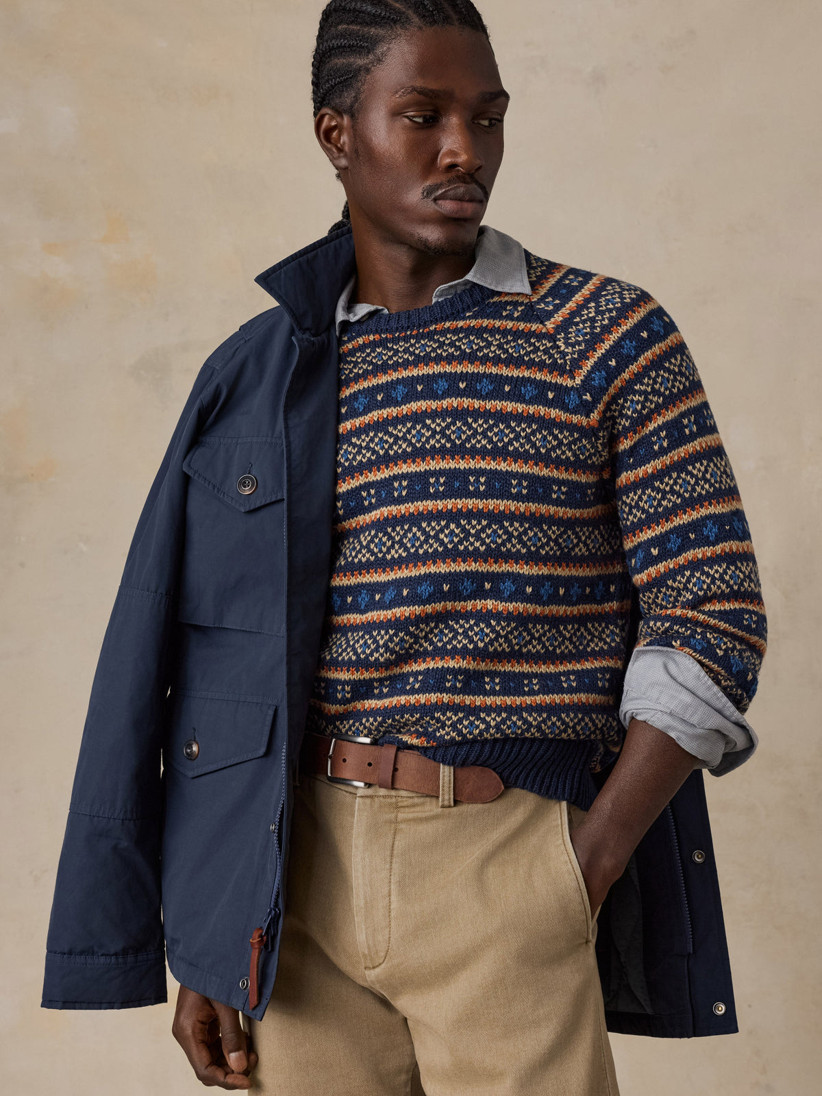 Male model wearing Faherty Nordic Sweater Crew in Northern Nights Fairisle pattern with navy jacket and khaki trousers