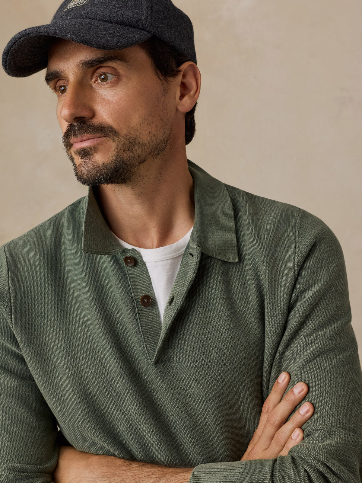 Male model wearing Faherty mountain green lightweight sunwashed sweater polo with navy cap