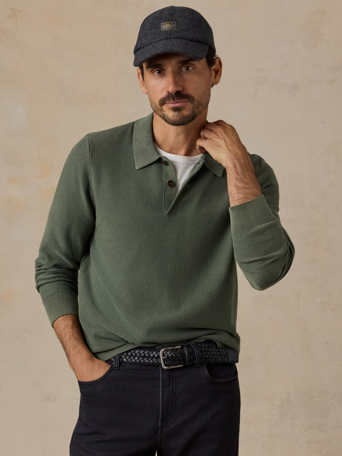Male model wearing Faherty mountain green lightweight sunwashed sweater polo with dark cap and jeans