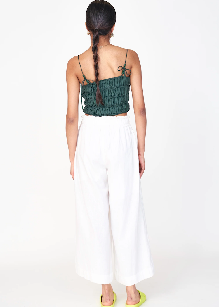 Woman wearing white wide-leg pants with green ruched top, shown from behind
