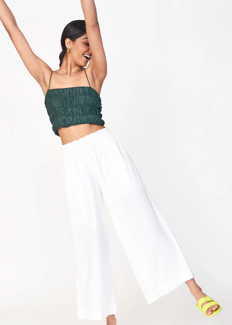 Woman wearing white wide-leg Mirth pants with green ruched crop top