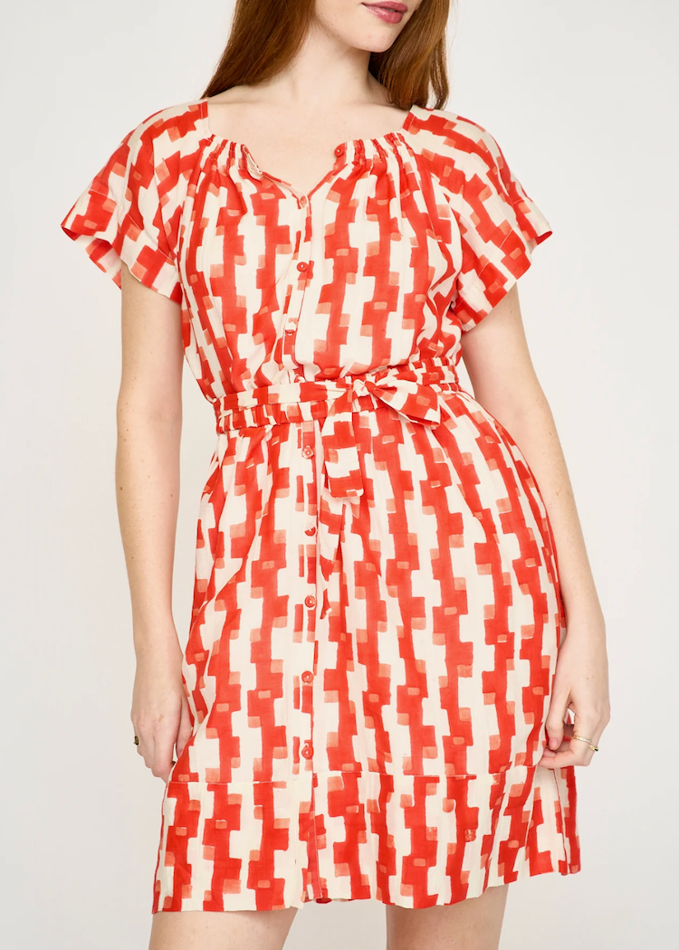 Woman wearing red and cream geometric print short dress with flutter sleeves and tie waist