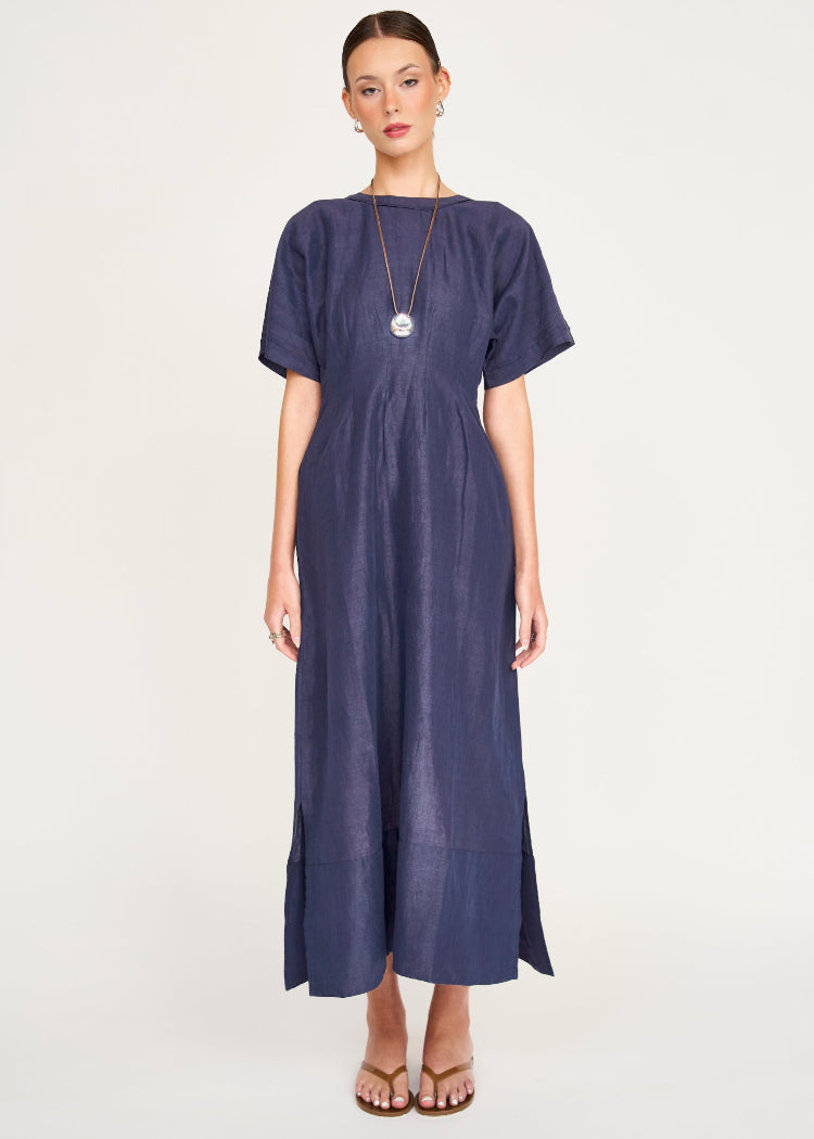 Woman wearing navy blue midi dress with short sleeves and long pendant necklace