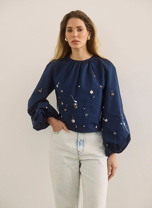 Model wearing navy blue embellished balloon sleeve blouse with light wash jeans
