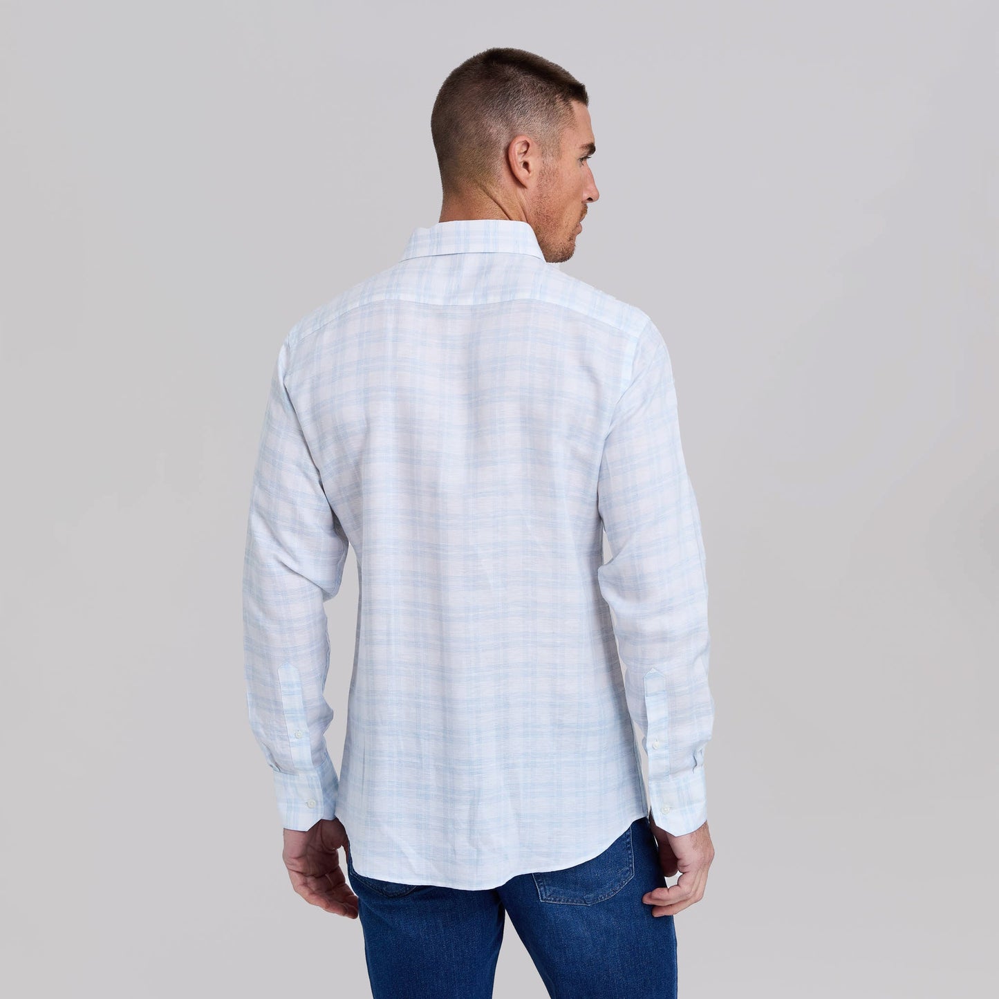Man wearing light blue and white plaid dress shirt viewed from behind