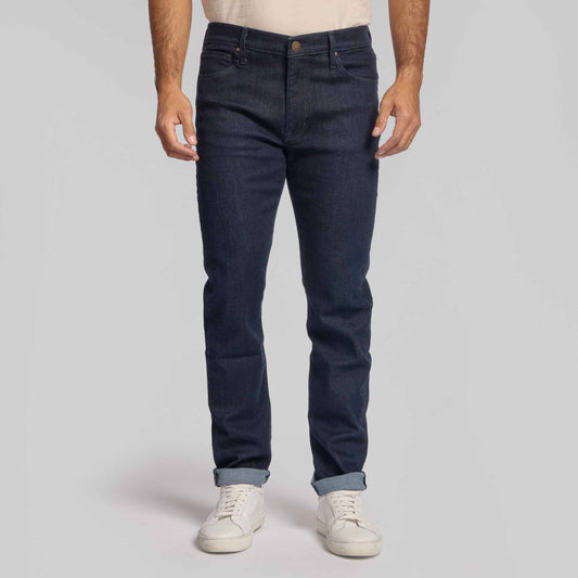 Man wearing dark indigo 4-way stretch jeans with white sneakers and cuffed hem