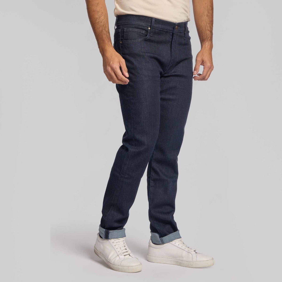 Male model wearing dark indigo slim-fit stretch jeans with white sneakers