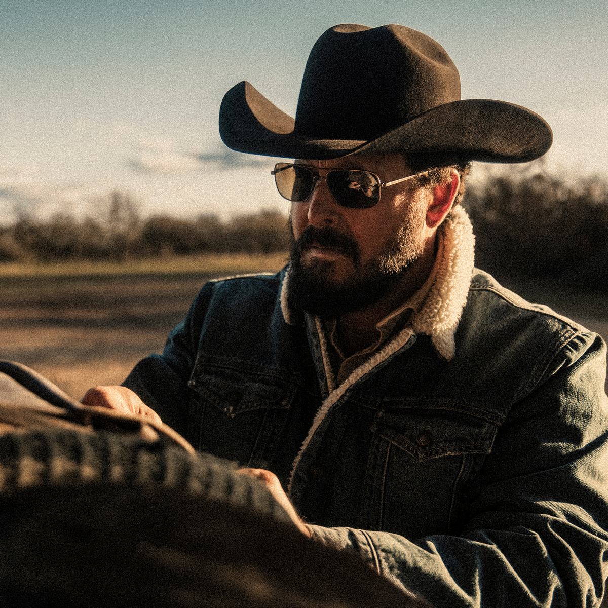 Man wearing Randolph x Cole Hauser Frontier sunglasses in antique bronze with cowboy hat