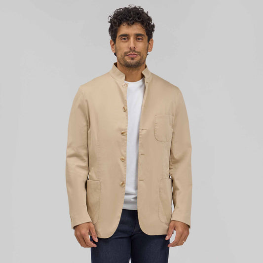 Man wearing tan 5-button mandarin collar blazer jacket over white t-shirt and dark jeans
