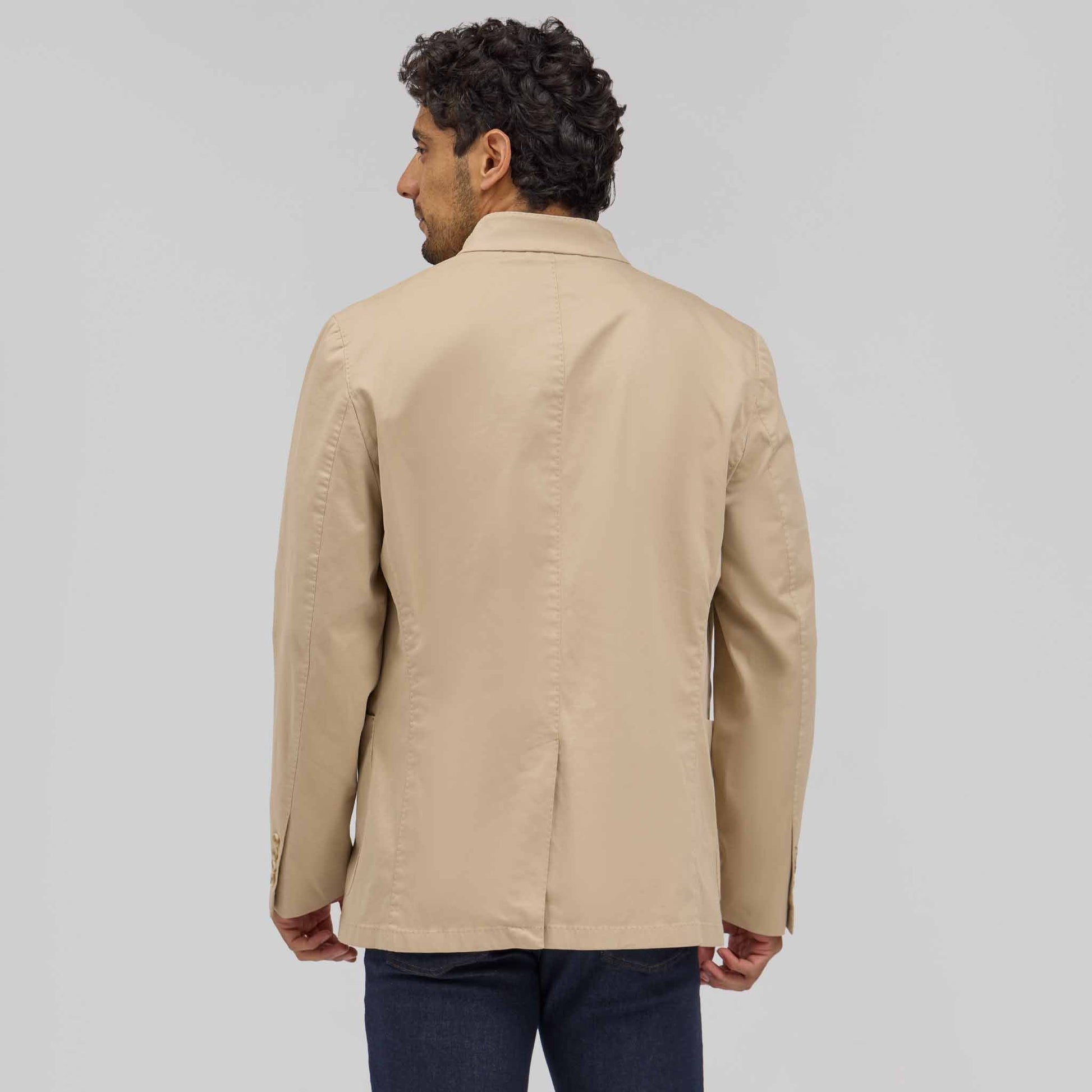 Back view of man wearing tan Drago 5-button mandarin jacket with dark jeans