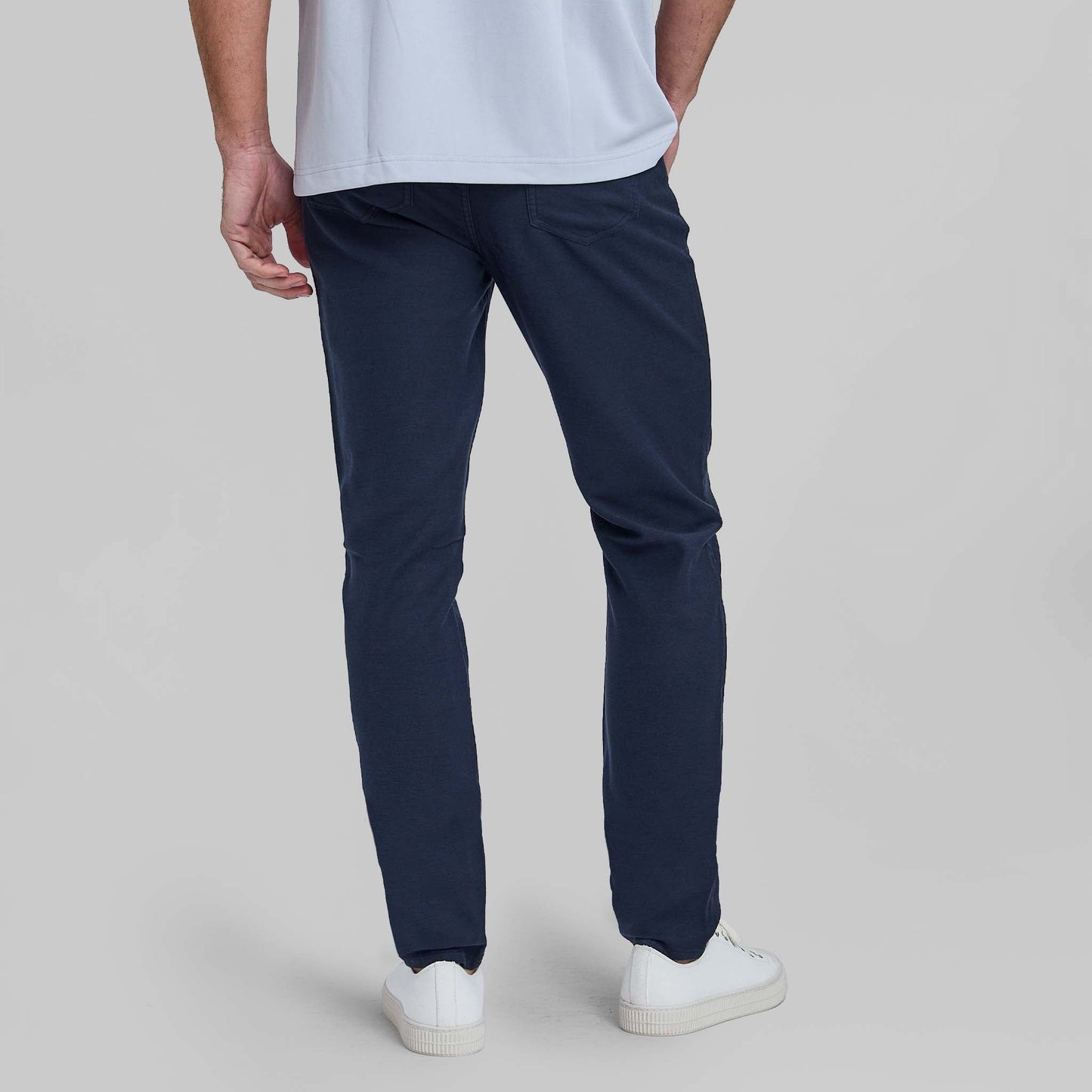 Man wearing navy blue feather terry five pocket pants with white sneakers