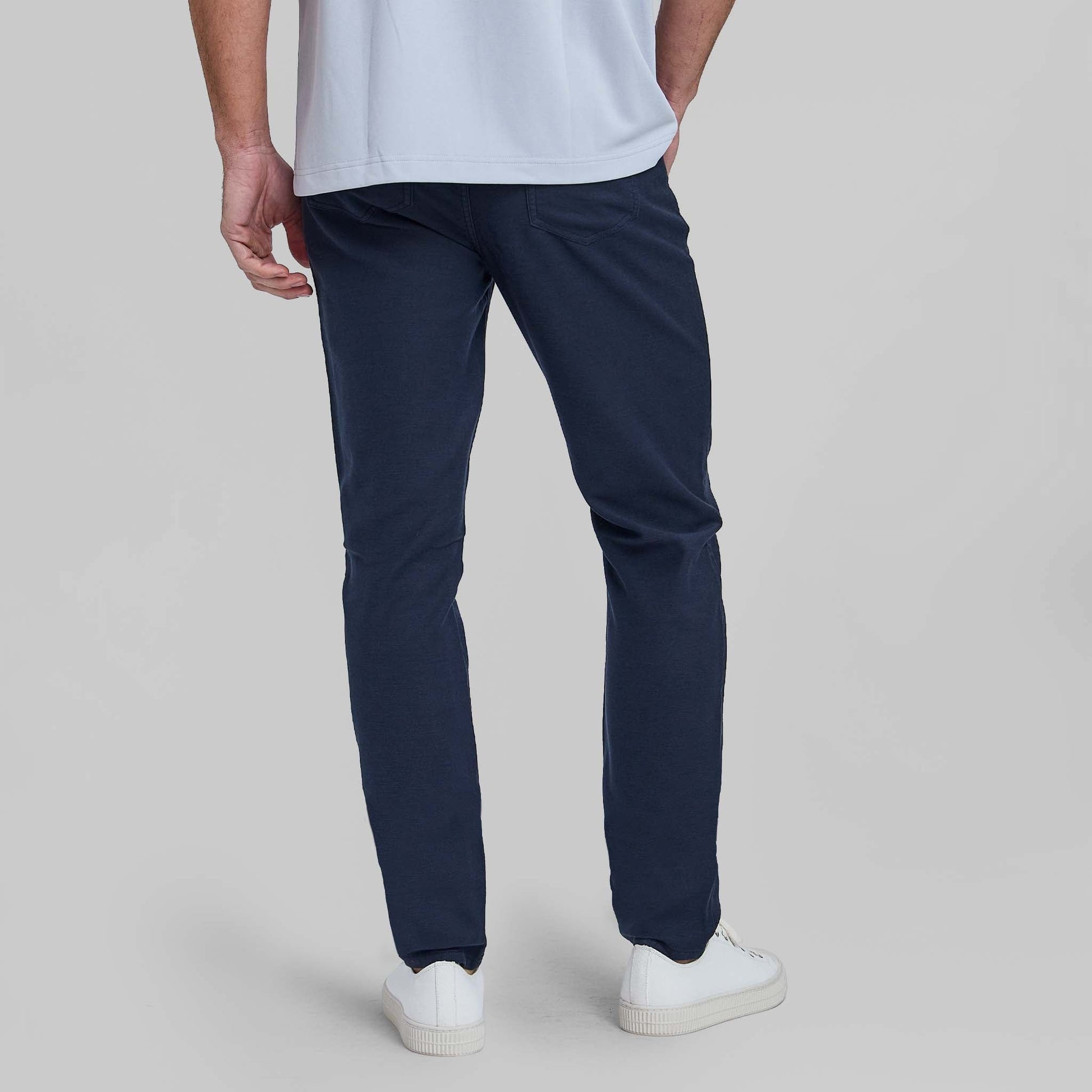 Man wearing navy blue feather terry five pocket pants with white sneakers