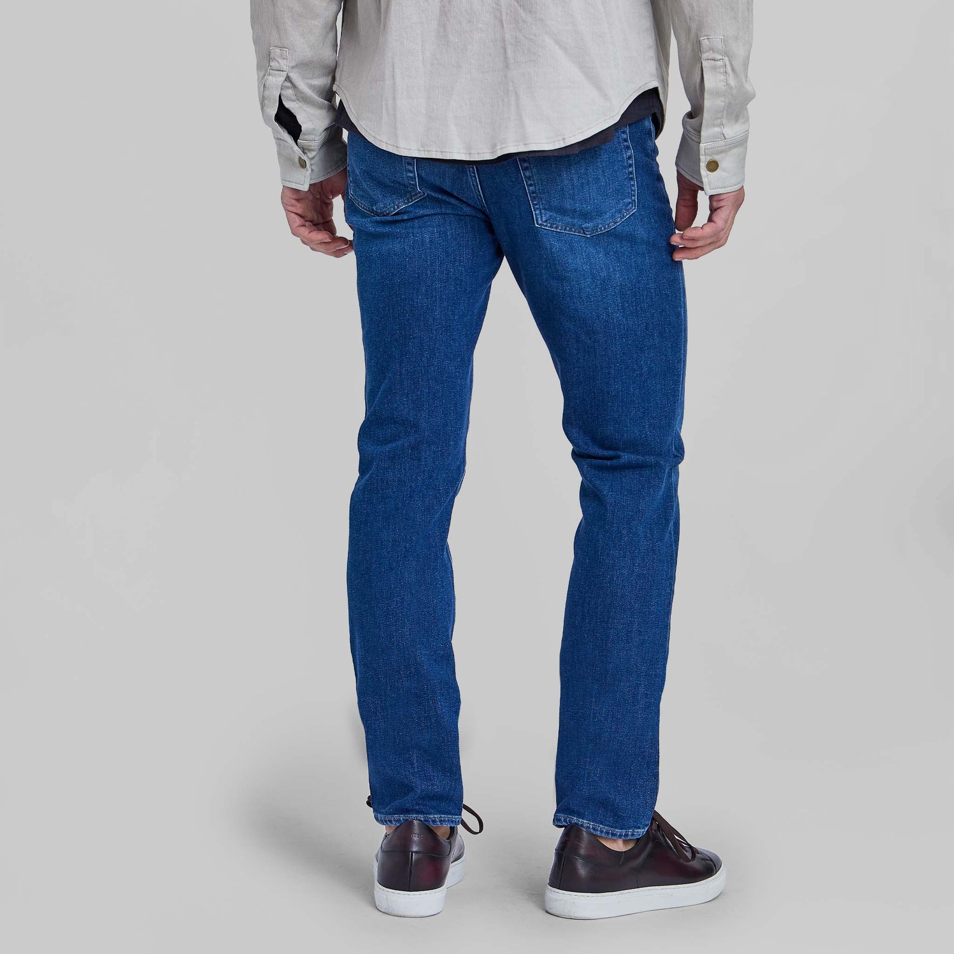 Man wearing medium blue stretch denim jeans from behind showing fit and wash