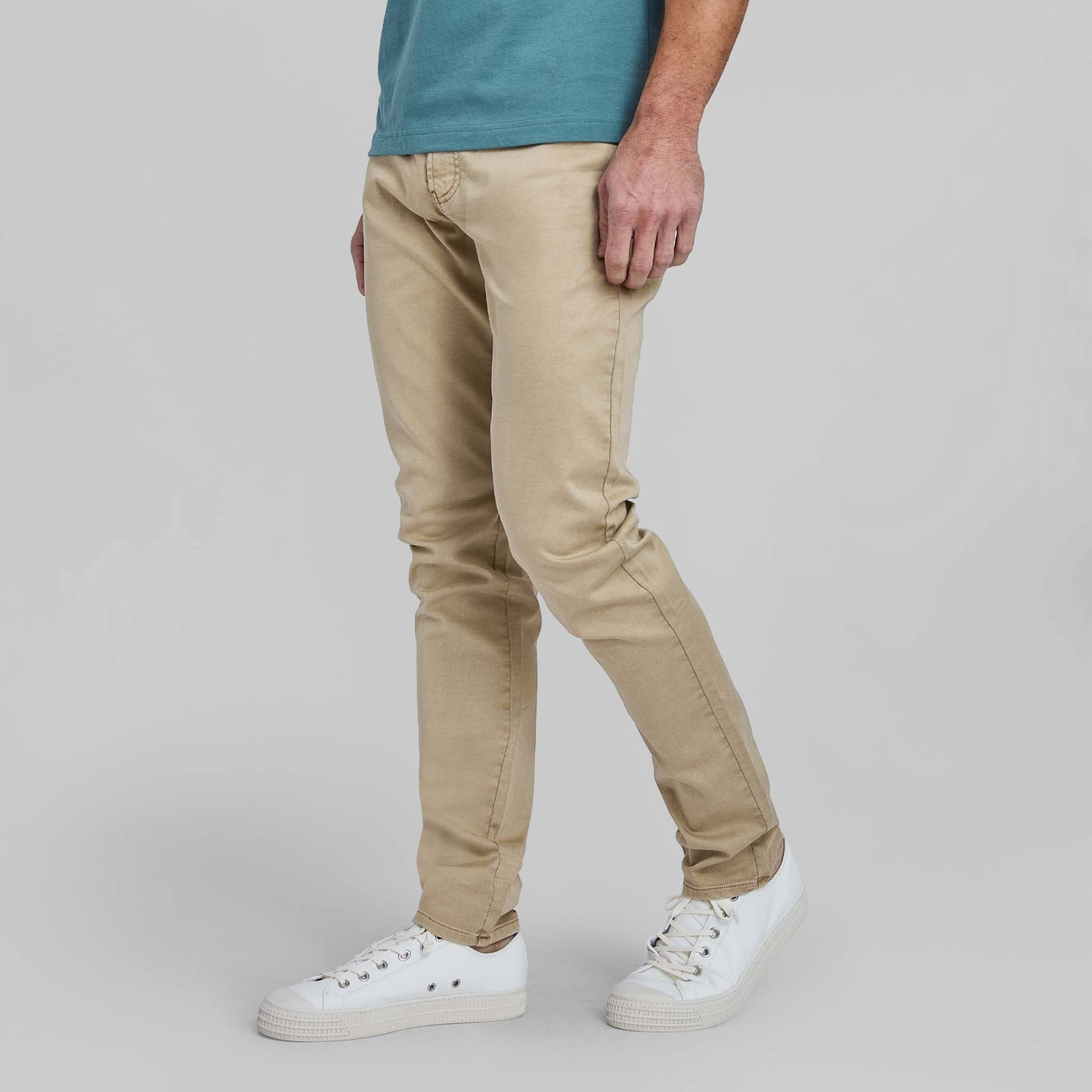 Model wearing wheat colored flex terry comfort stretch 5-pocket pants with white sneakers