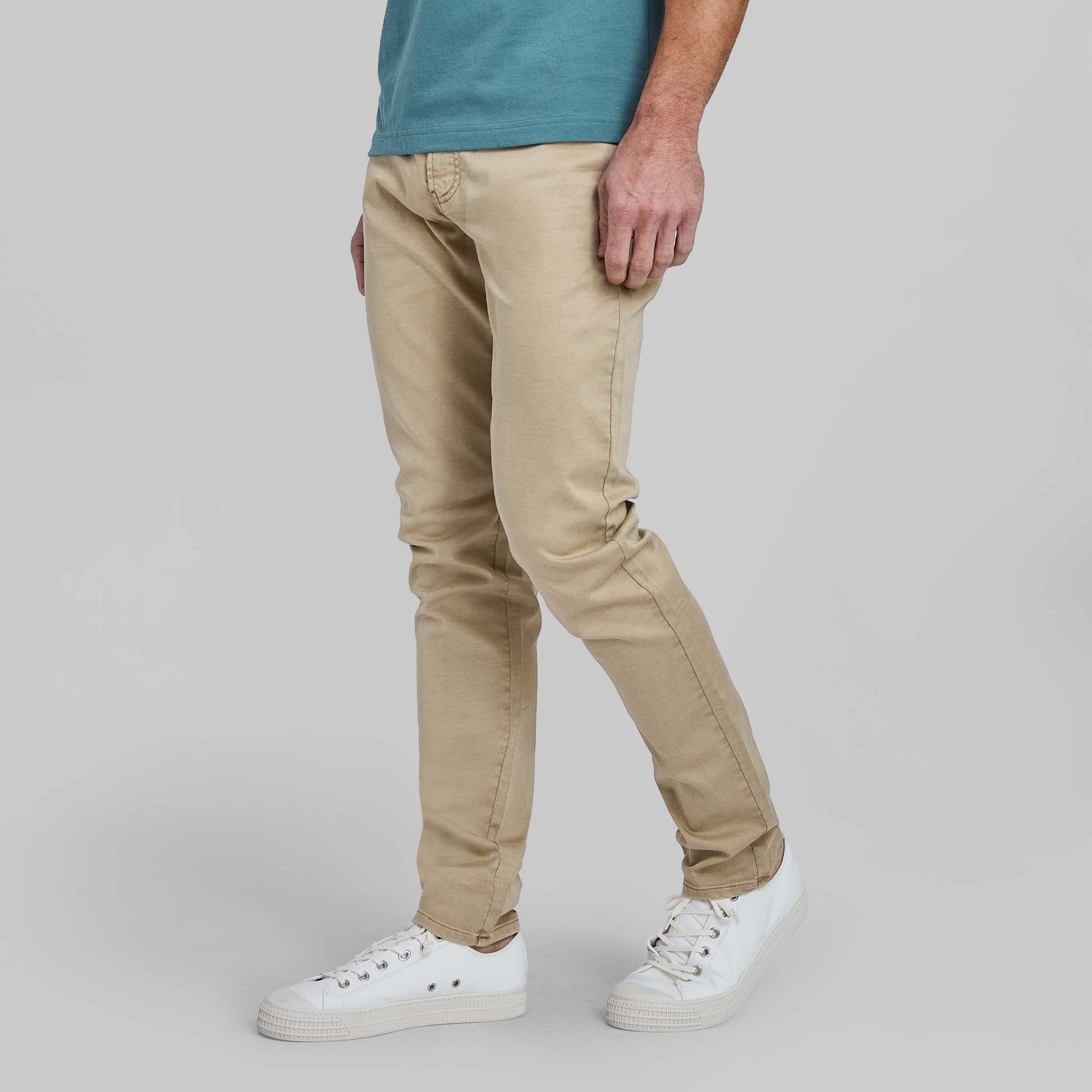 Model wearing wheat colored flex terry comfort stretch 5-pocket pants with white sneakers