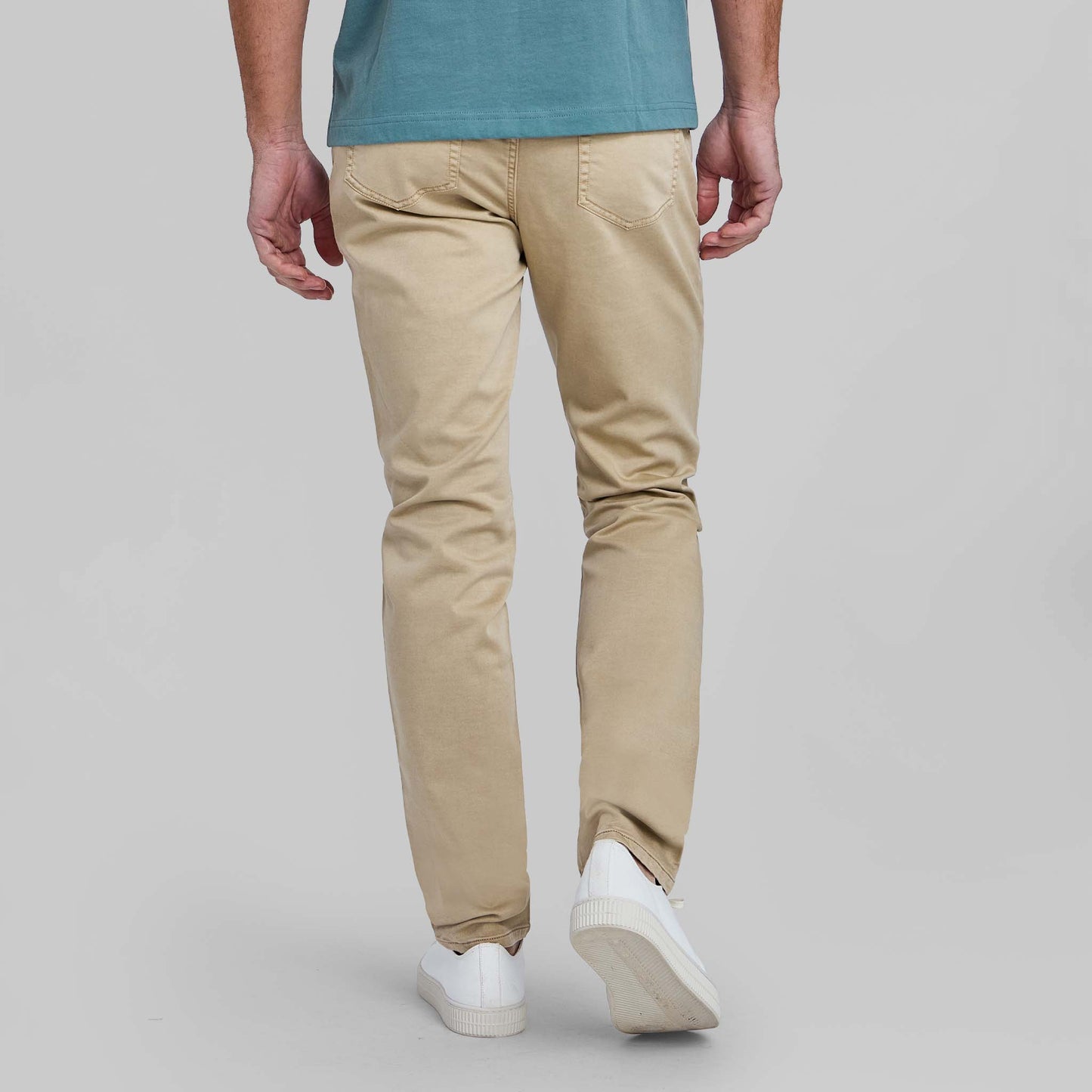 Back view of man wearing wheat colored stretch pants with white sneakers