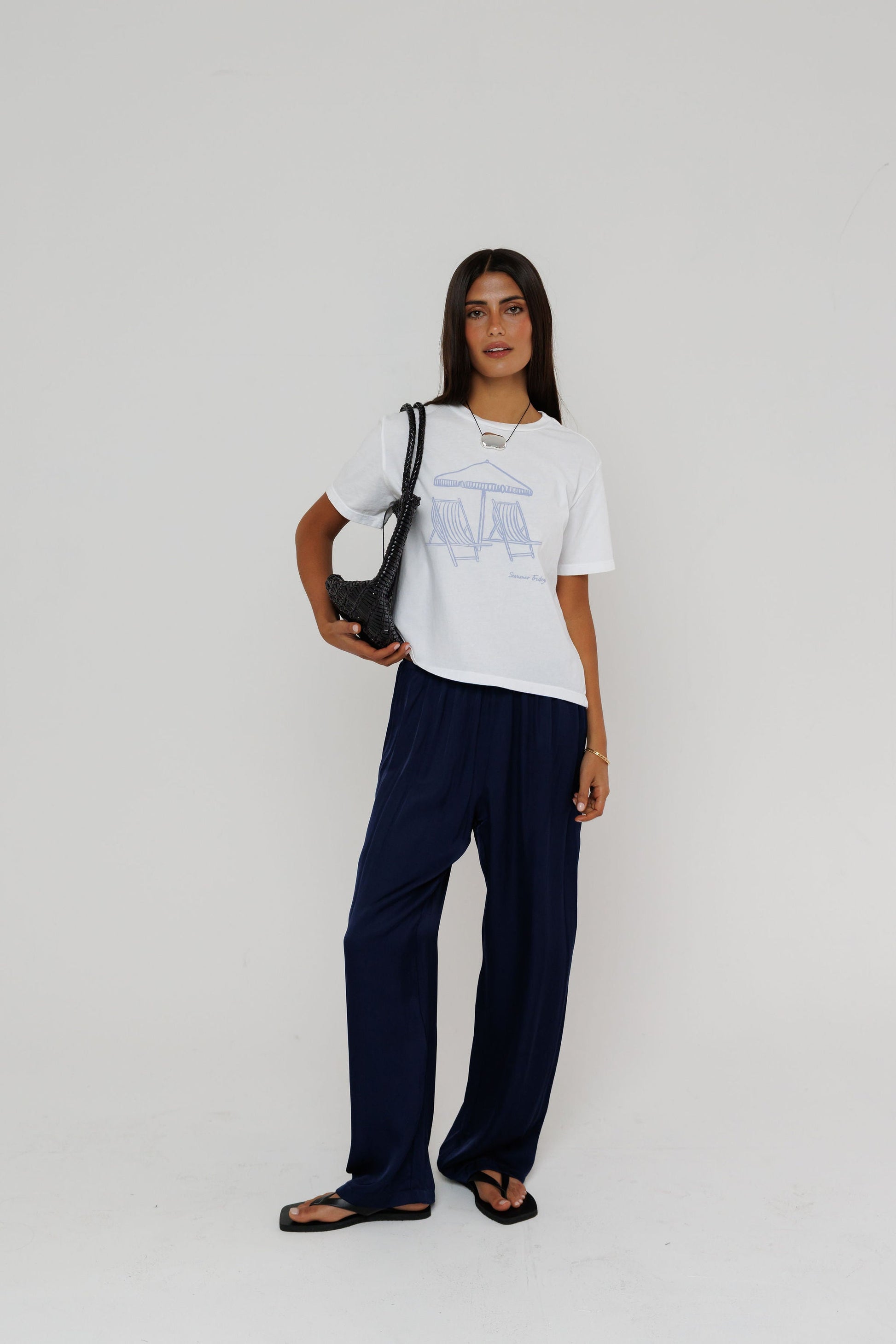 Model wearing white Summer Fridays graphic tee with navy wide-leg trousers and black sandals