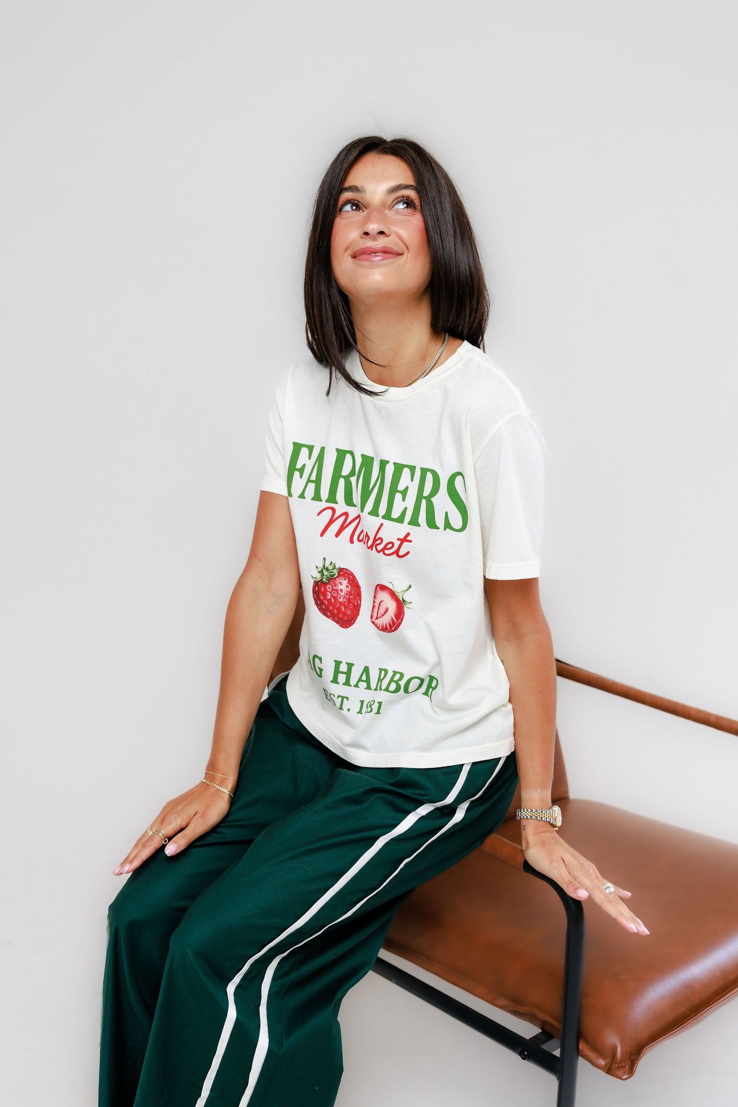 Model wearing cream Sag Harbor Farmers Market graphic tee with green track pants
