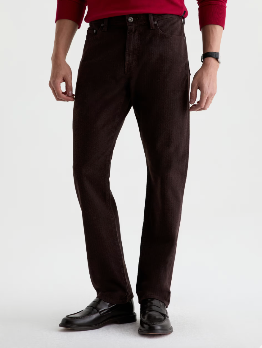 AG Everett straight-leg dark brown jeans styled with black penny loafers and a red long-sleeve top.